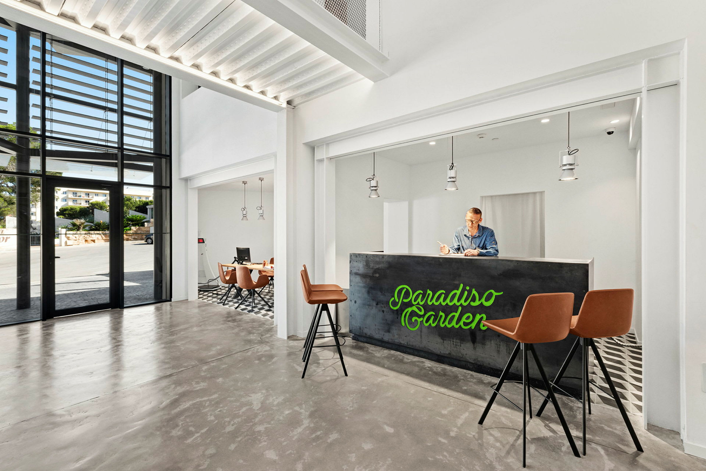 Ett modernt hotelllobbyområde med receptionsdisk, barstolar och en sittgrupp i en ljus och luftig miljö. (AI-genererad text)