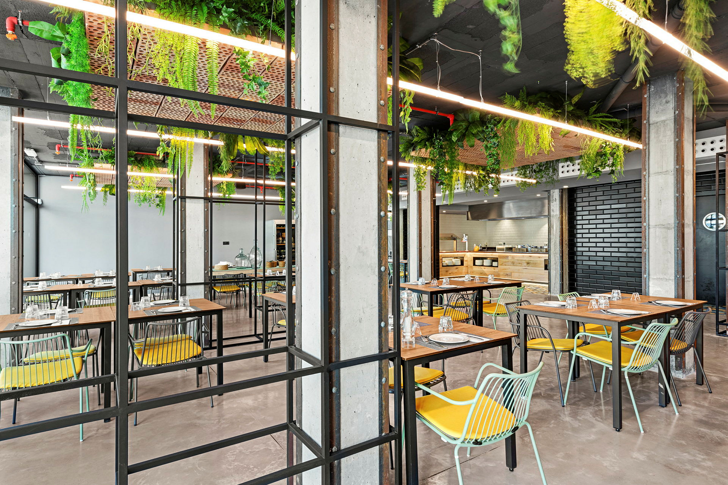 En modern restaurang med bord, stolar och grönska hängande från taket. (AI-genererad text)