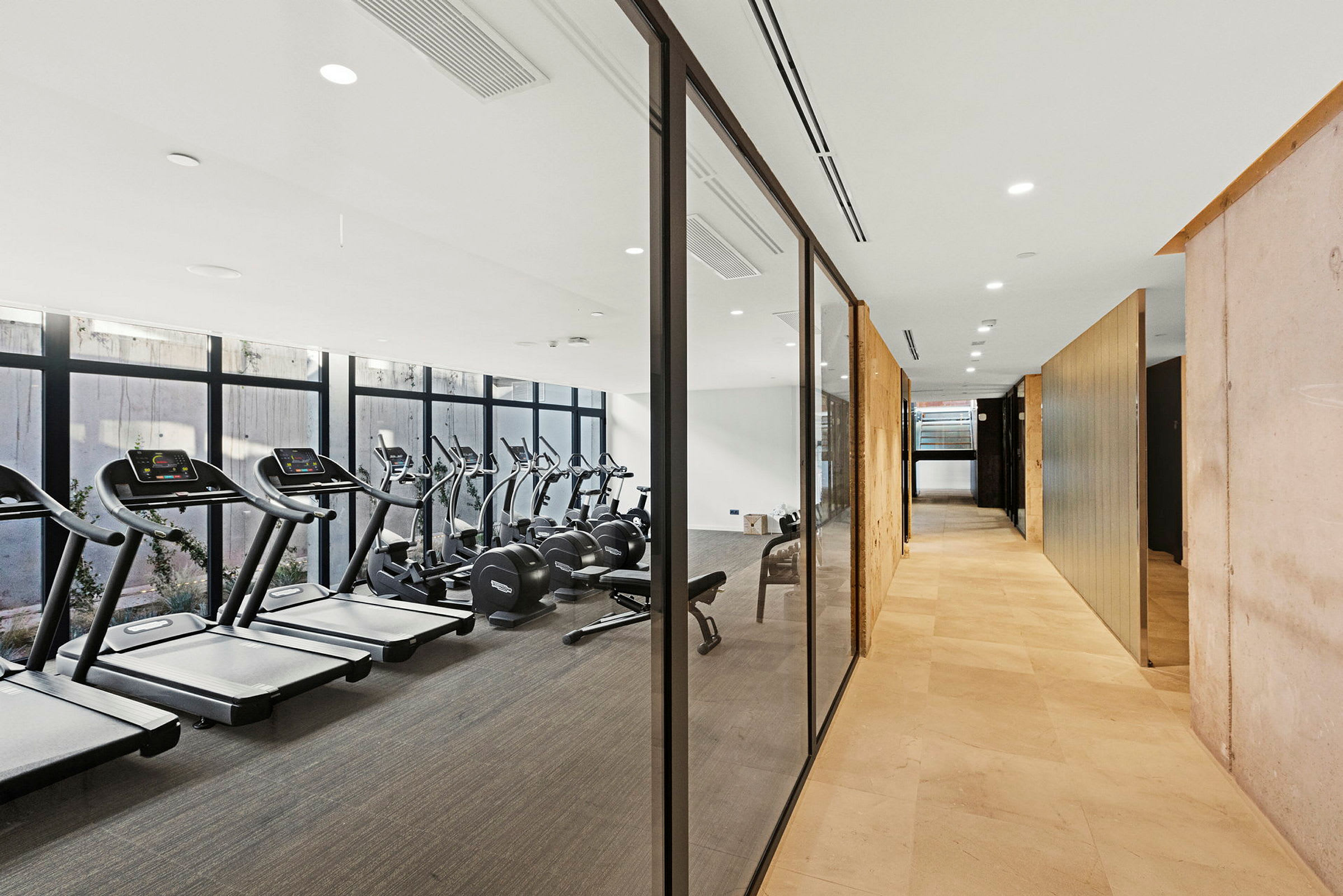 Bild av ett gym med glasväggar som delar det från en ljus hall. (AI-genererad text)