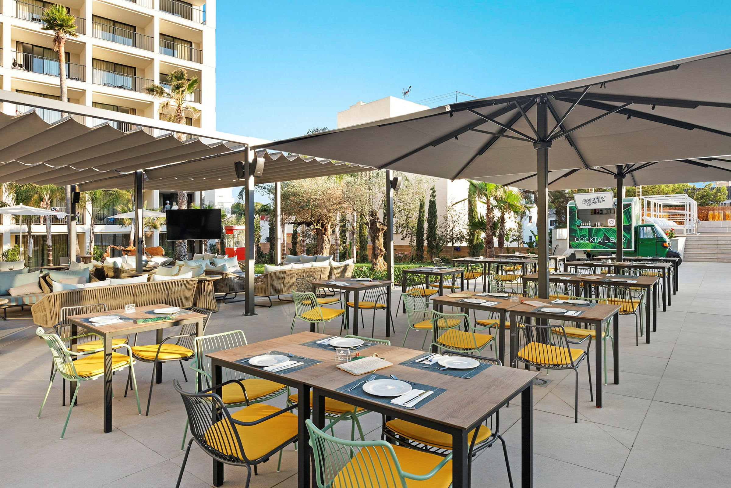 En utomhusrestaurang med dukade bord, sittplatser och stora parasoller. (AI-genererad text)