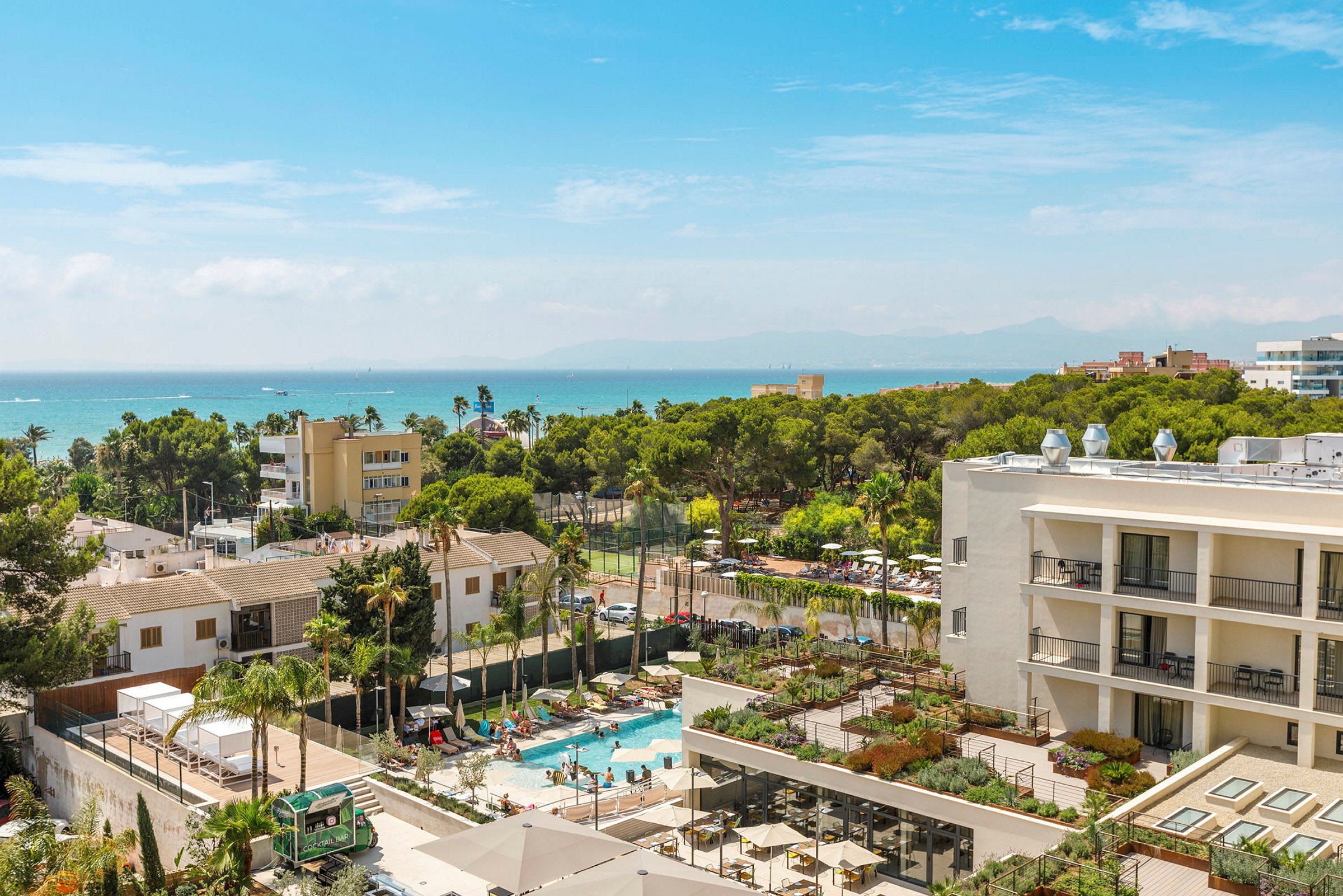 Bild av en hotellbyggnad med pool och gröna träd i bakgrunden, samt blå himmel. (AI-genererad text)