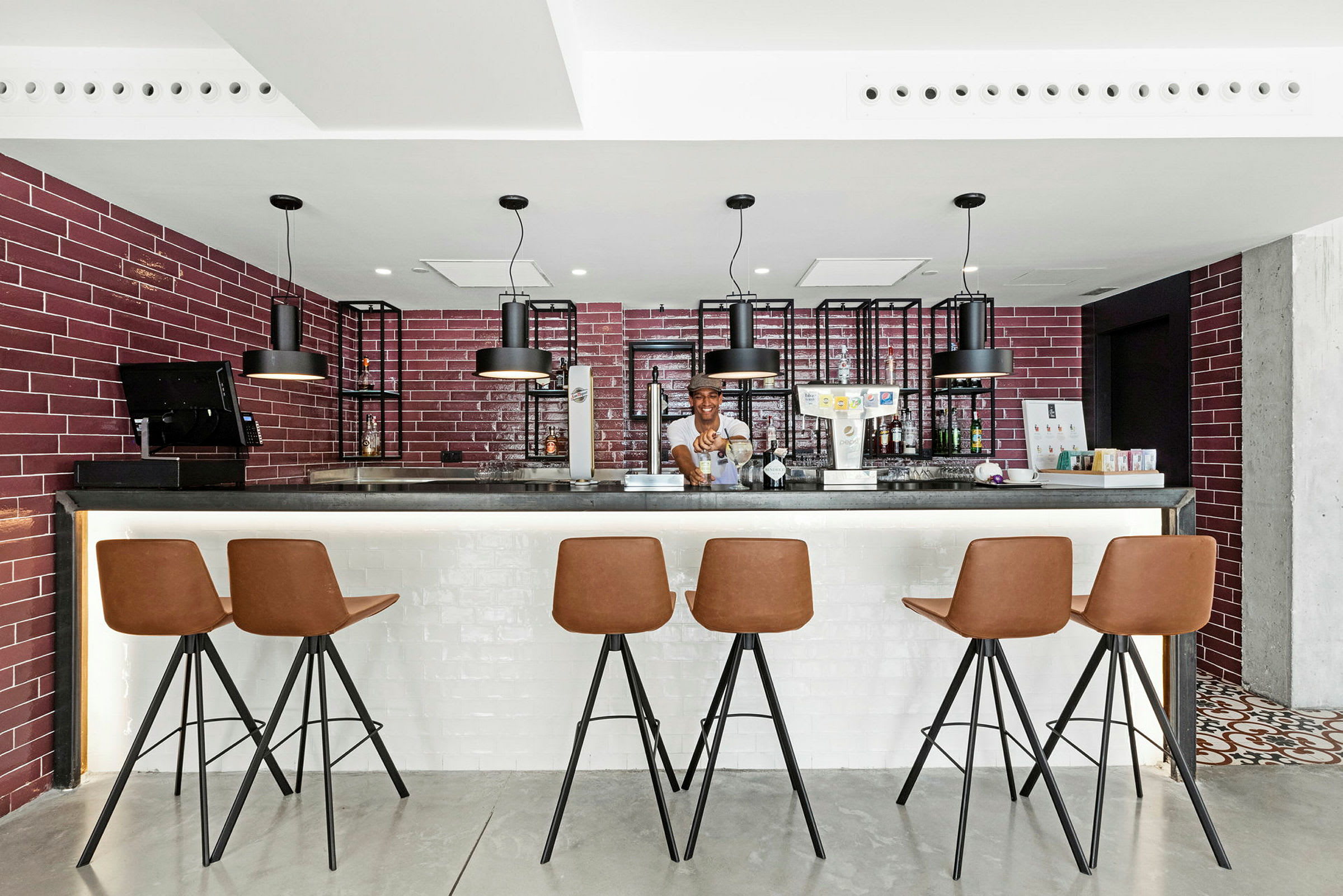 En modern bar med röda tegelväggar, upplyst bardisk och bruna stolar. (AI-genererad text)