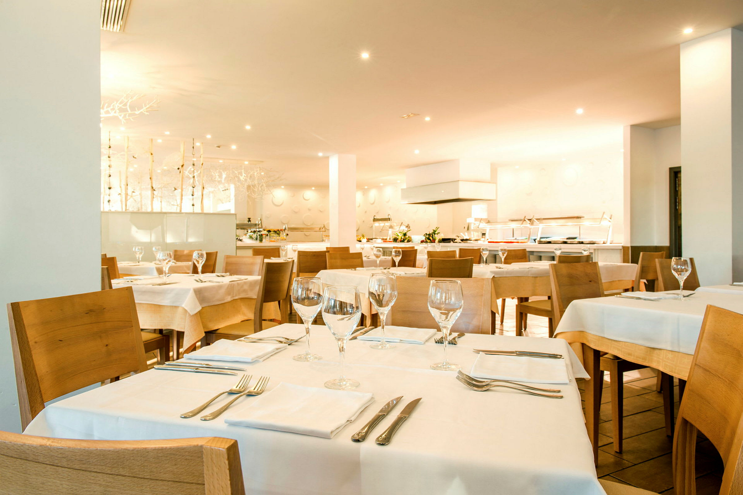 En restauranginteriör med flera dukade bord och trästolar. (AI-genererad text)
