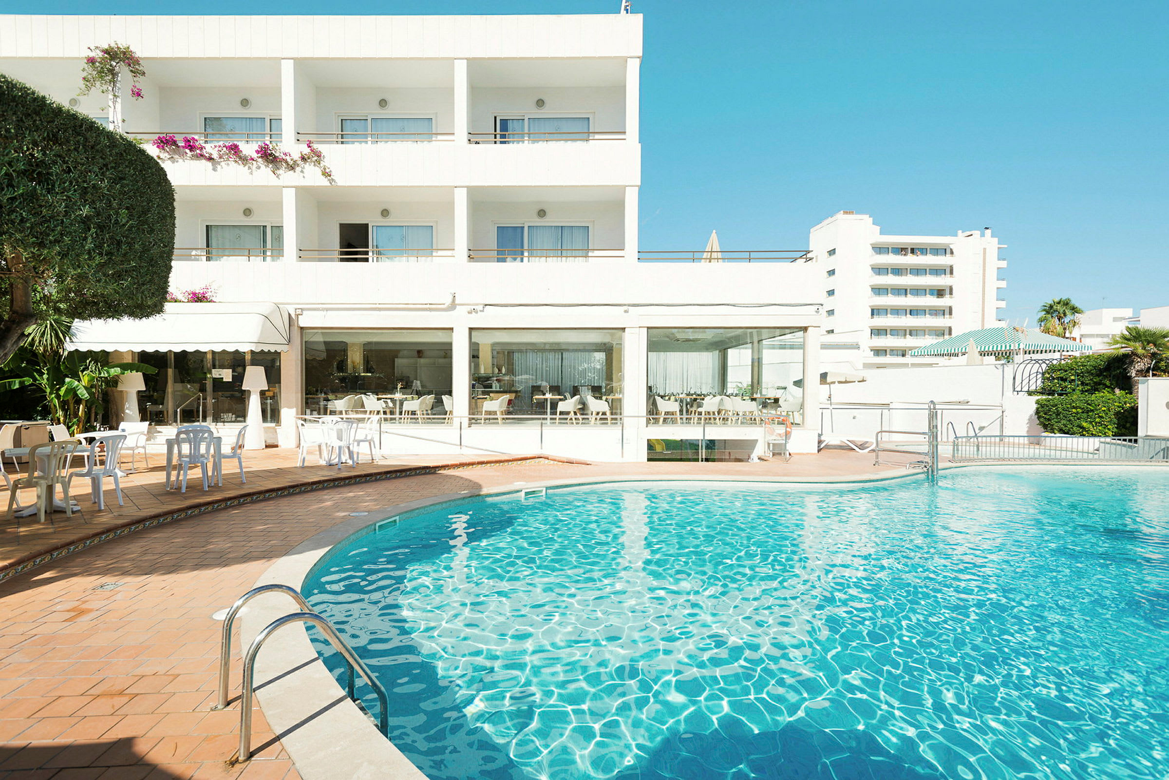 Hotellbyggnad med en utomhuspool i förgrunden. (AI-genererad text)