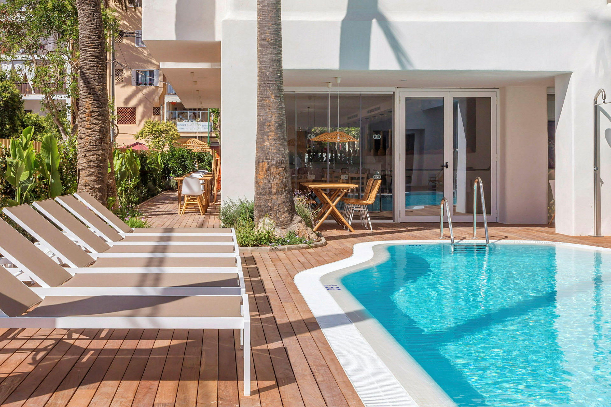 Pool med solsängar och restaurang i bakgrunden. (AI-genererad text)