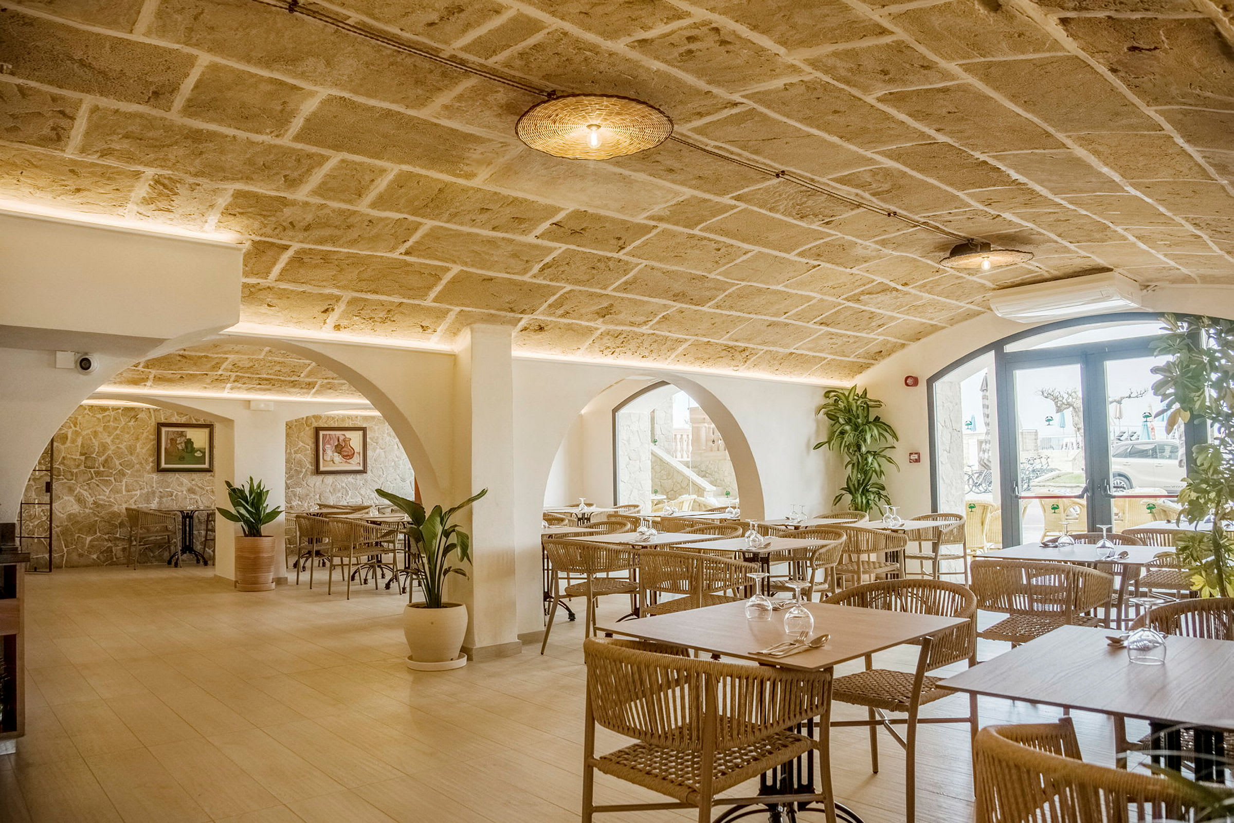 Interiör av en restaurang med stenvalv, moderna möbler och dekorativa växter. (AI-genererad text)