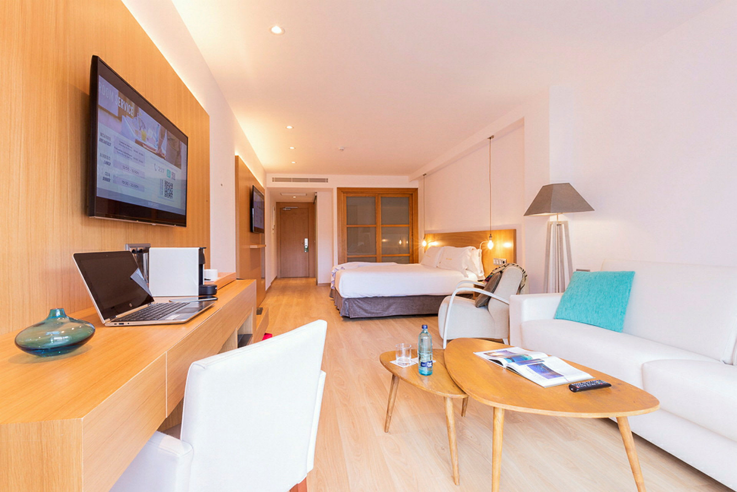 Ett elegant hotellrum med en stor säng, skrivbord, soffhörna och modern inredning. (AI-genererad text)