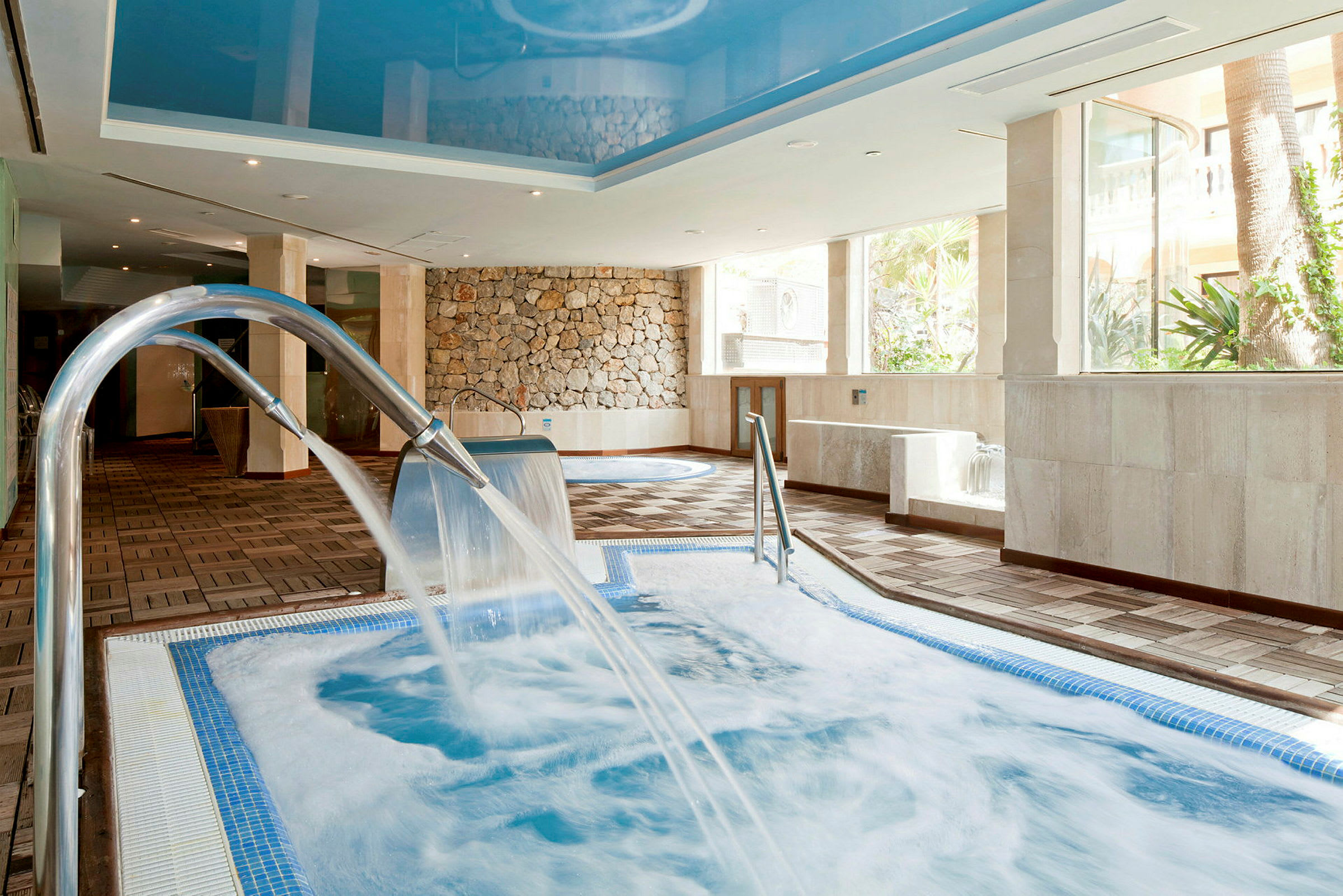 En inomhusspa med ett bubbelbad och vattenströmmar från kranar. (AI-genererad text)