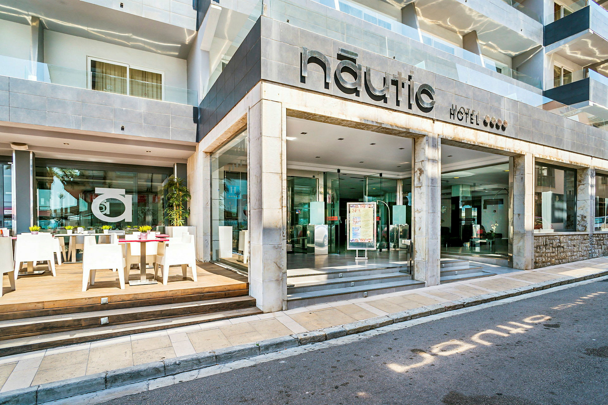 Hotel Nautic entré och uteservering med bord och stolar. (AI-genererad text)