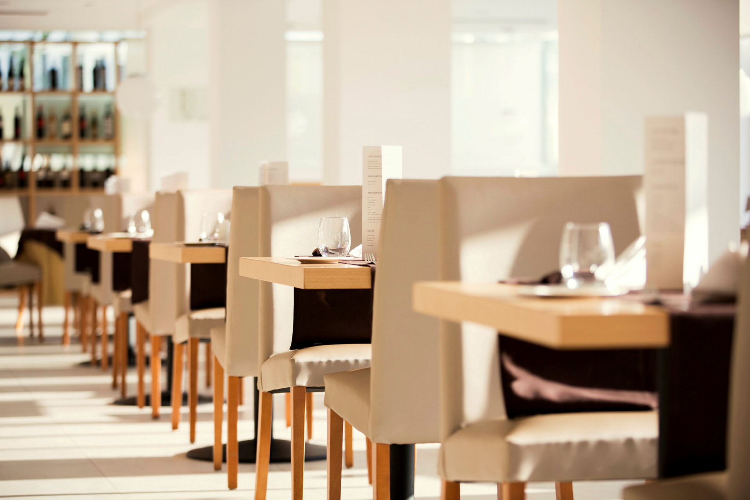 Interiör av en ljus och elegant restaurang med dukade bord och stolar. (AI-genererad text)