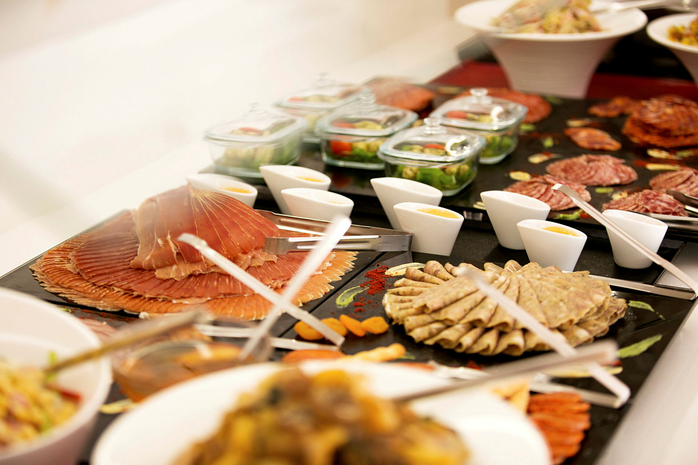 En buffé med olika charkuterier, sallad, sås och tillbehör presenterade på skålar och fat. (AI-genererad text)