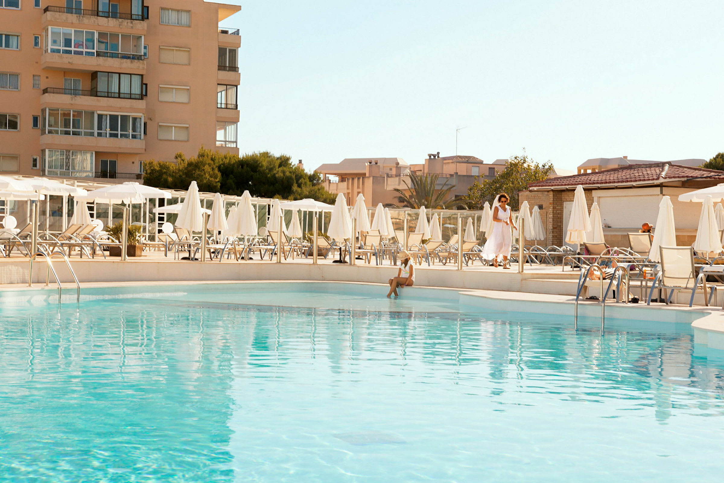 Utomhuspool vid hotell med omgivande solstolar och parasoller. (AI-genererad text)