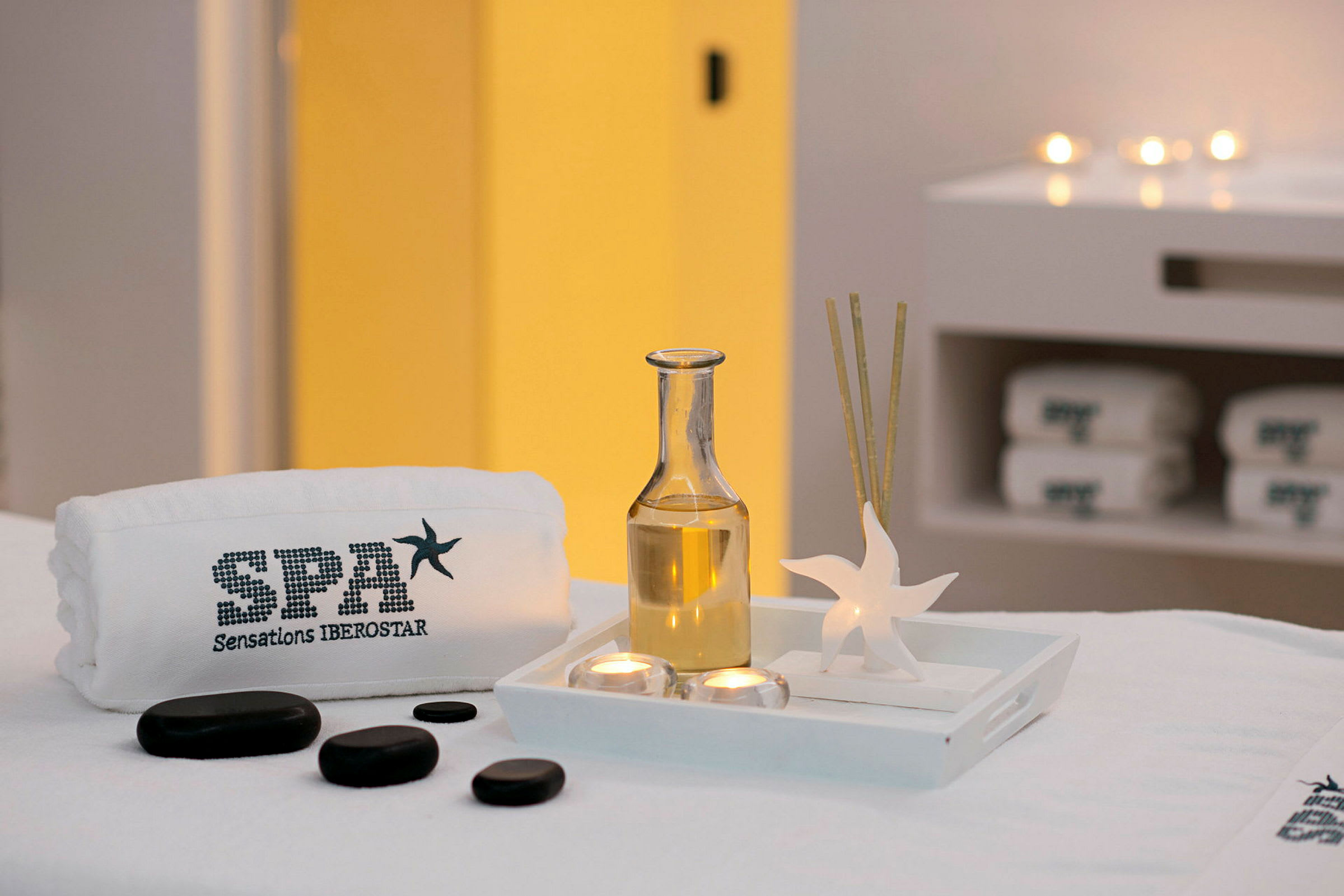 Ett spa-bord med spa-sten, handduk och aromaterapiaccessoarer i ett ljust rum. (AI-genererad text)