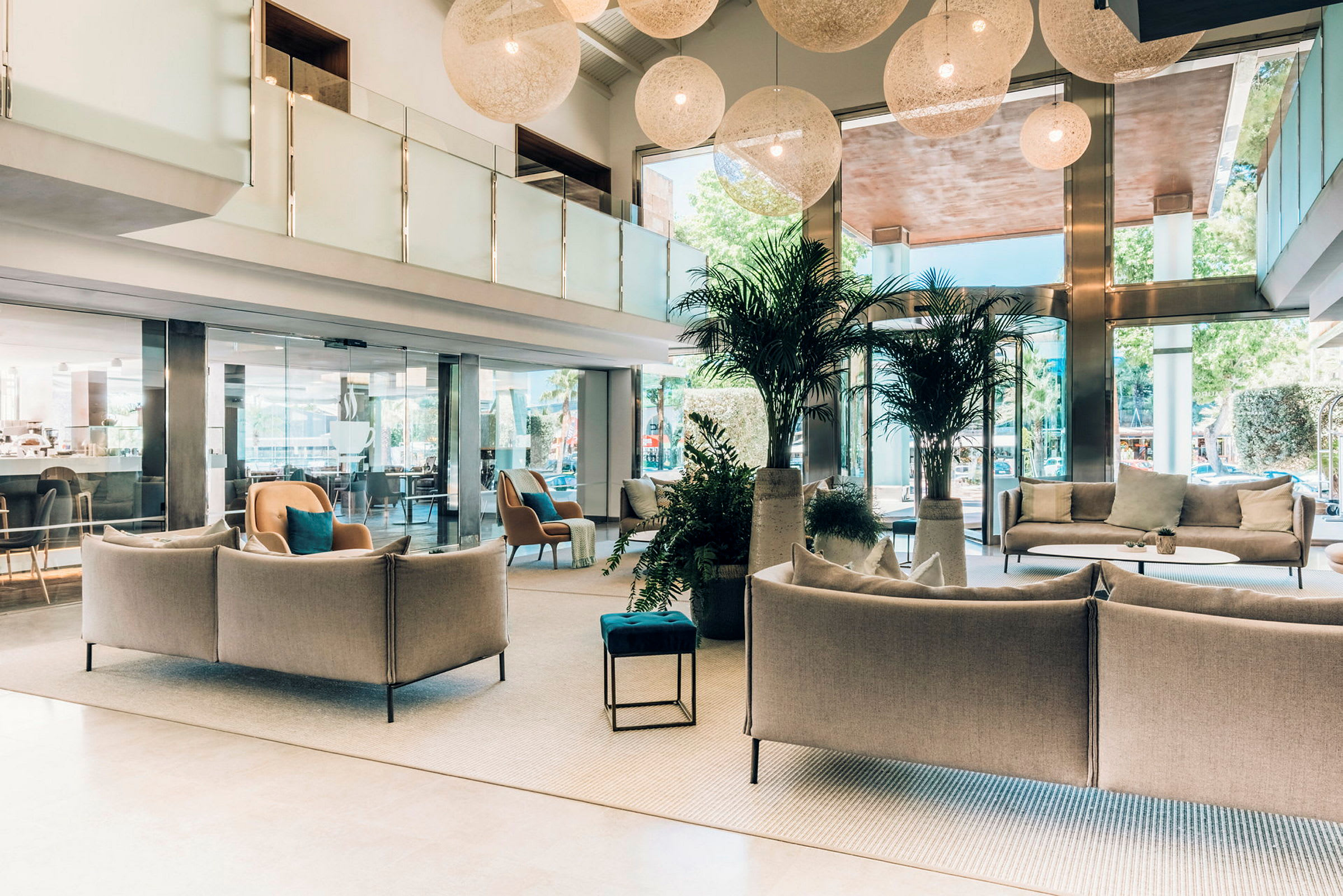 Ett modernt och ljust hotellobbyområde med sittgrupper, växter och stora fönster. (AI-genererad text)