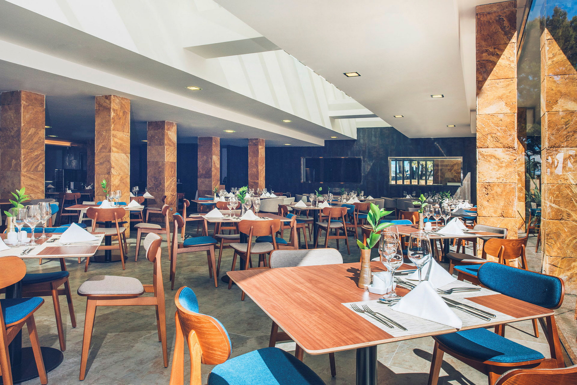 En elegant restaurang med träbord, blå stolskuddar och dukade bord. (AI-genererad text)