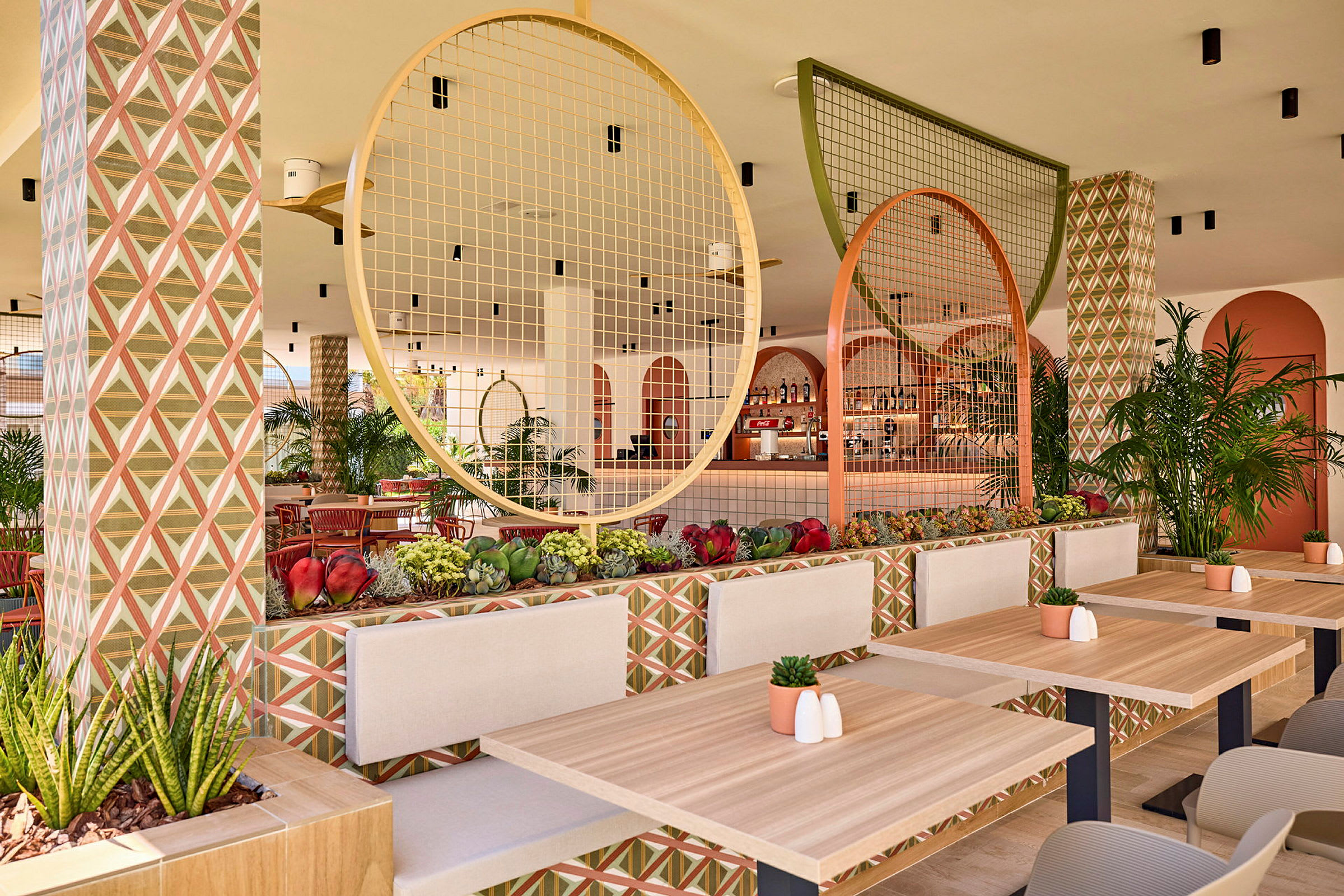 En välutformad restaurang med träbord, geometriskt mönstrade väggar och dekorativa cirkulära detaljer. (AI-genererad text)