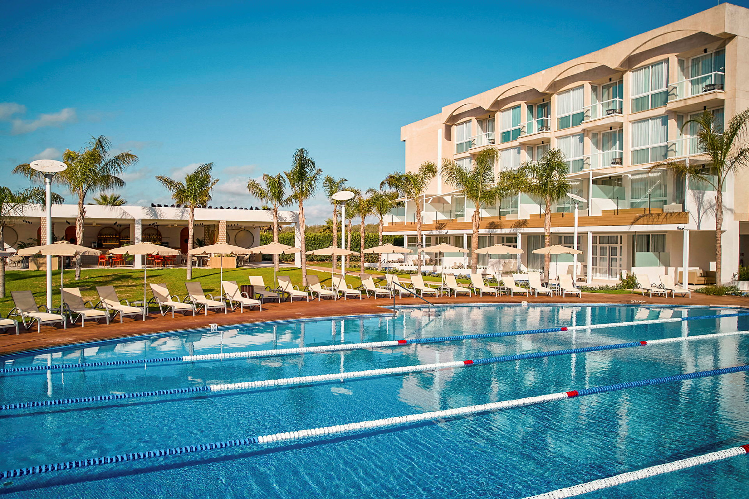 Hotell med pool och solstolar i förgrunden. (AI-genererad text)