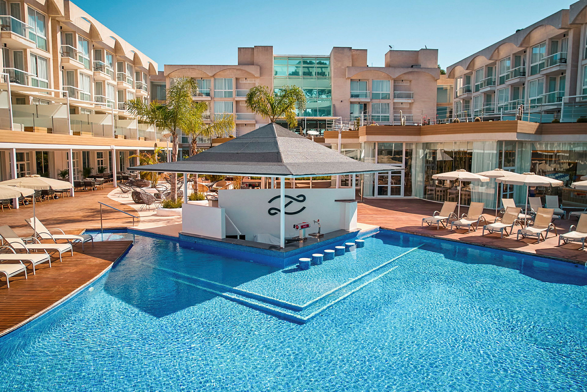 Bild av ett hotellområde med en utomhuspool, solstolar och en poolbar. (AI-genererad text)