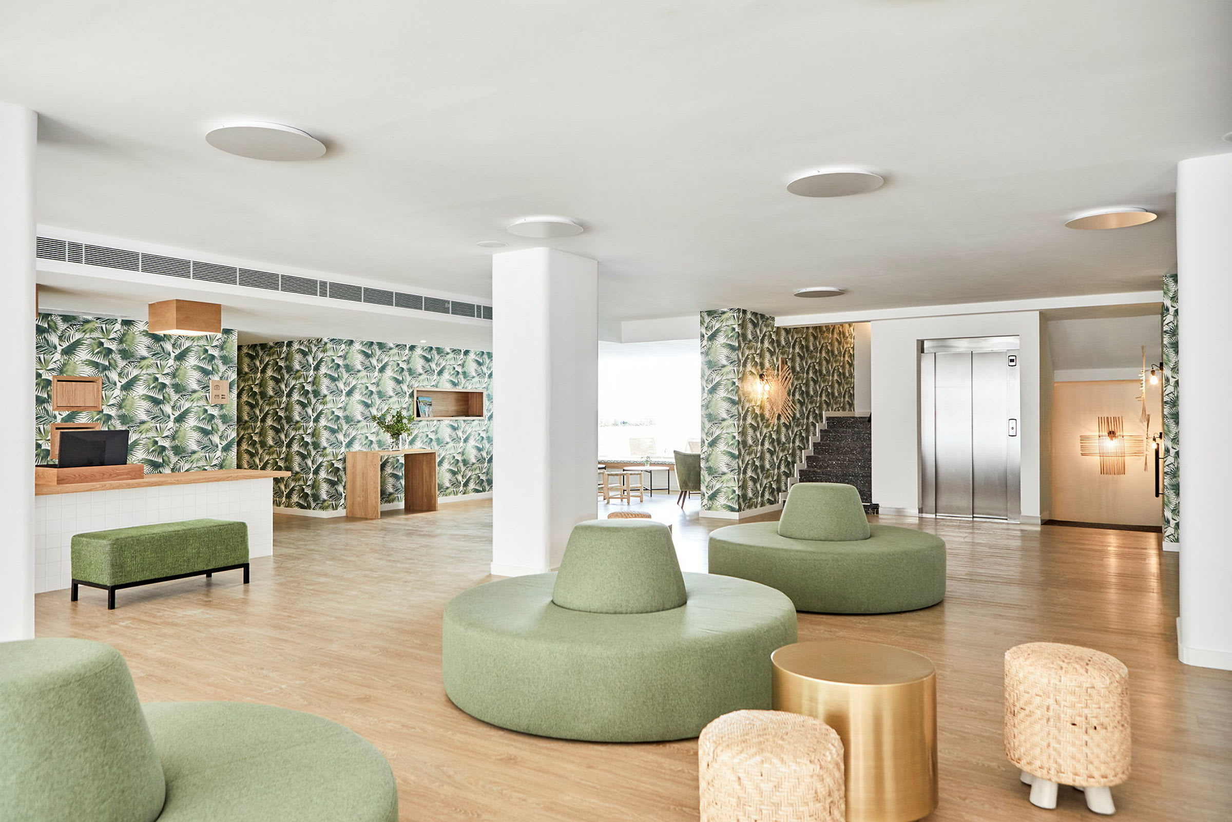 Modern lobby med gröna sittmöbler och växtmönstrade tapeter. (AI-genererad text)