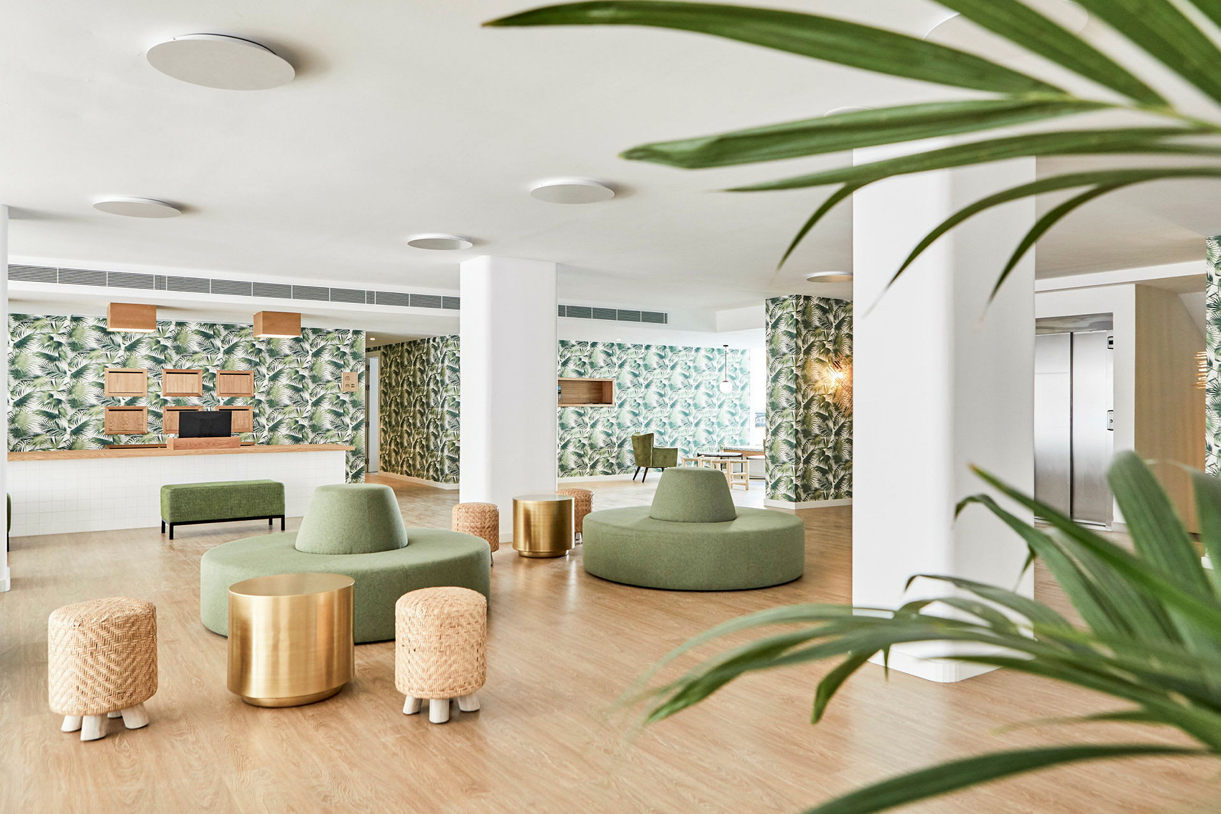 Modernt hotellobby med gröna möbler, väggar dekorerade med mönster av palmtblad och trädetaljer. (AI-genererad text)