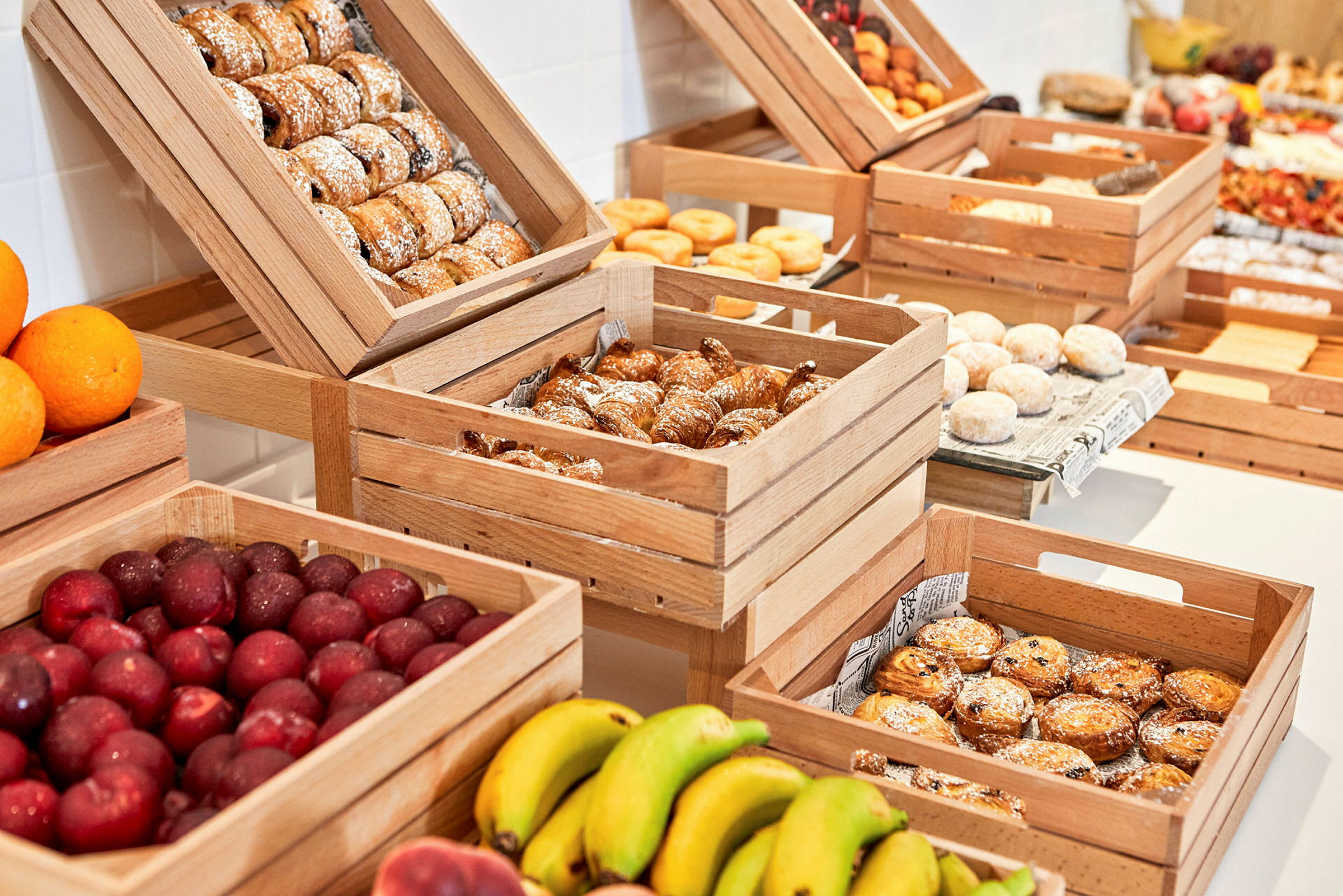 En display med olika färska frukter och bakverk i trälådor. (AI-genererad text)