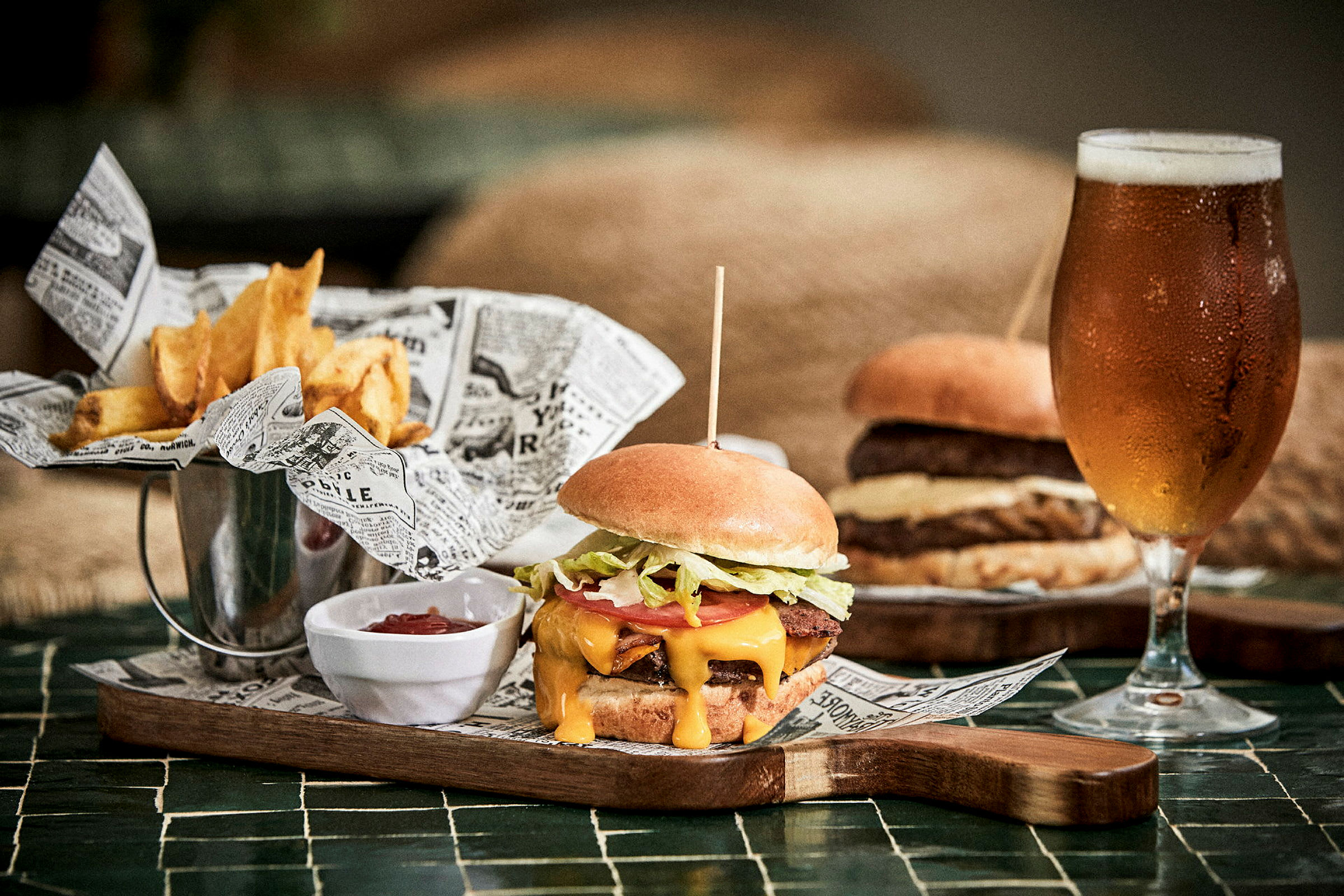 En hamburgare, pommes frites och en glas öl på ett bord. (AI-genererad text)