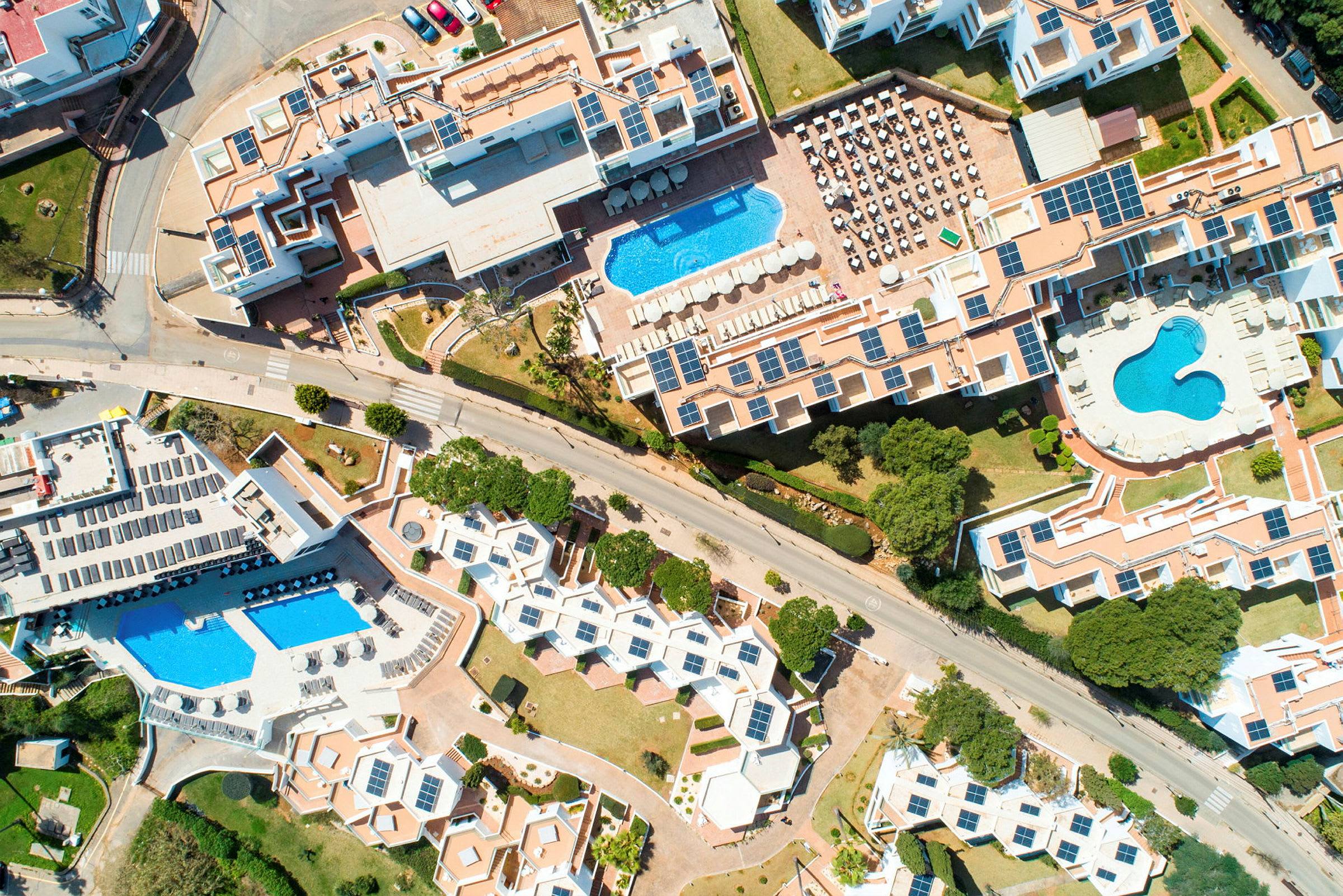 Flygbild av ett hotellområde med pooler och solpaneler. (AI-genererad text)
