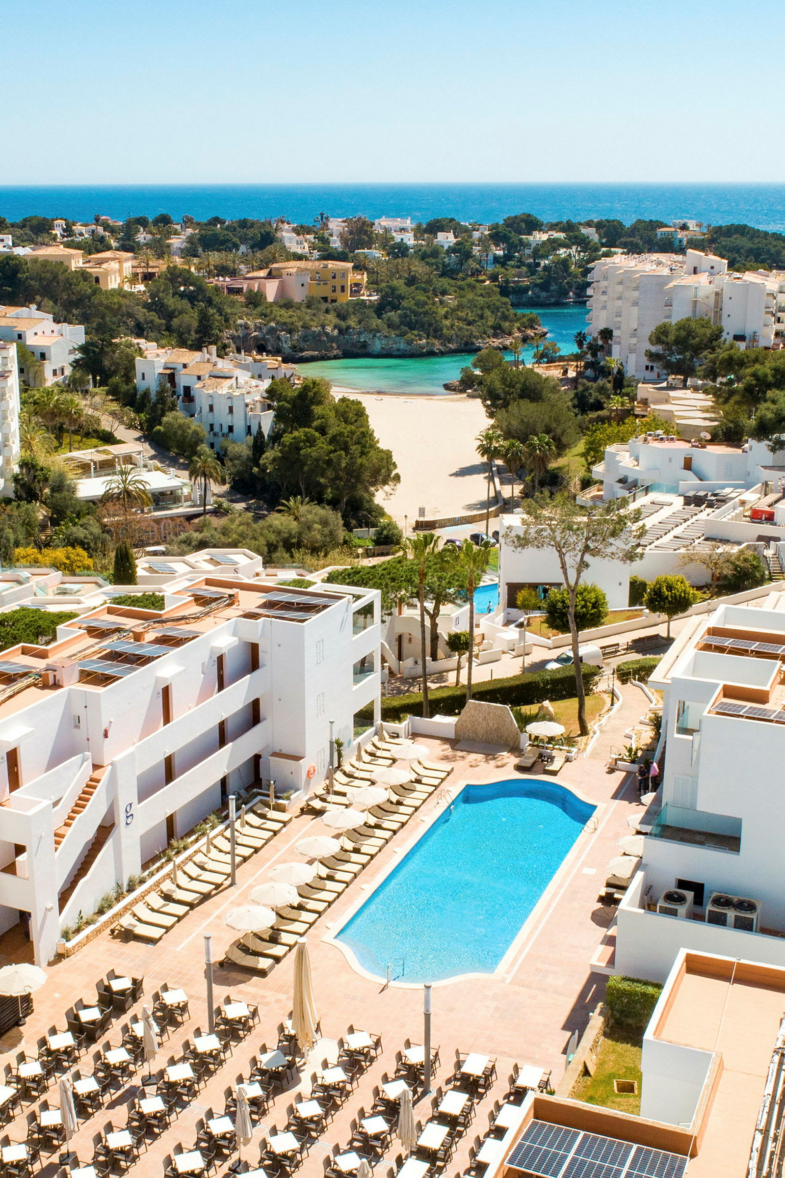 Hotellområde med pool och utsikt över en sandstrand och hav. (AI-genererad text)