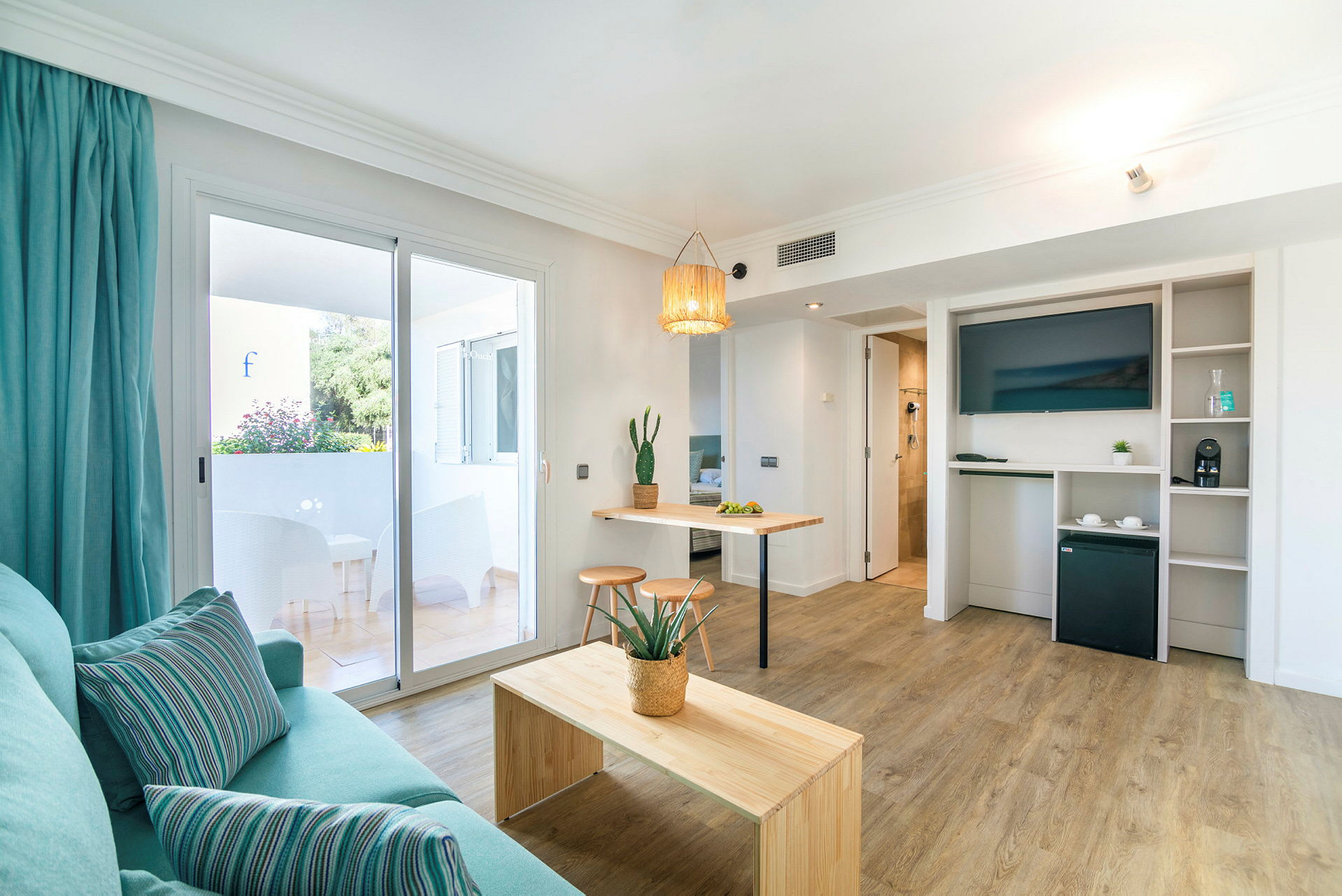 Modernt inrett hotellrum med träbord, TV, och balkong. (AI-genererad text)