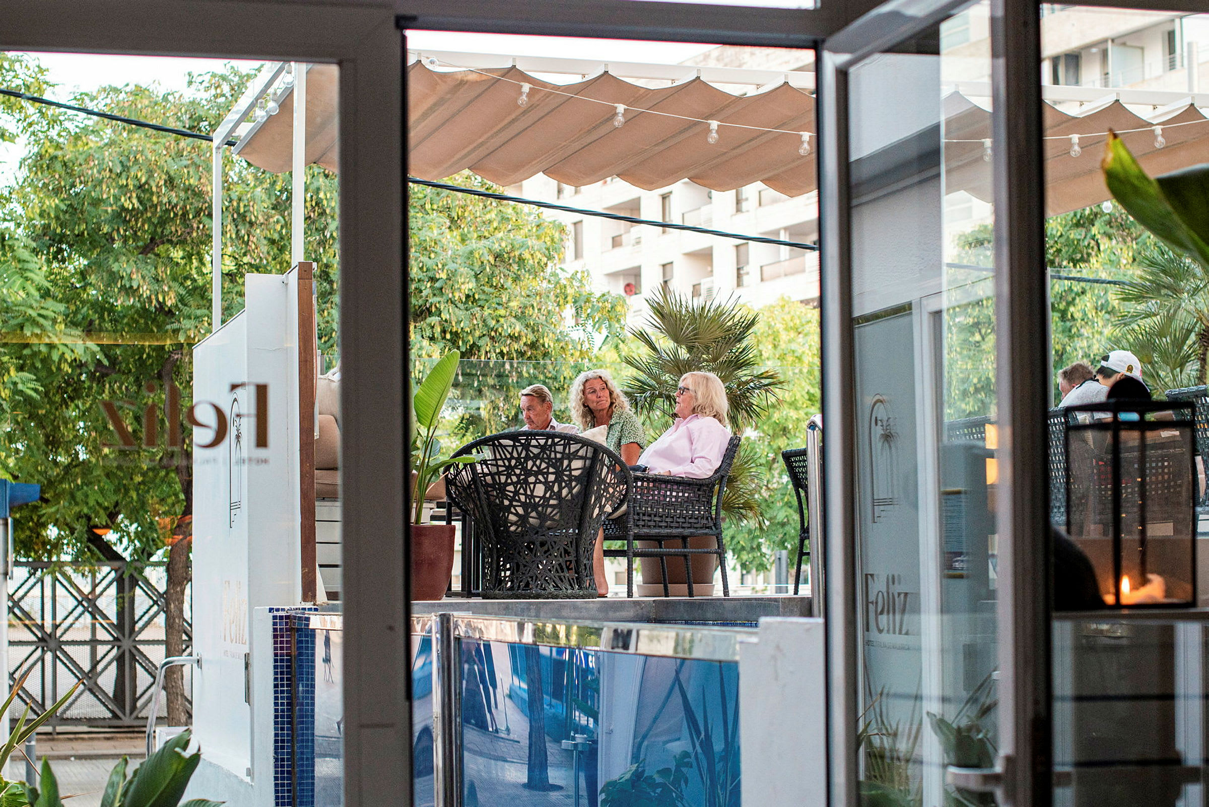 Personer sitter på en kaféutomhus i grönskande omgivning. (AI-genererad text)