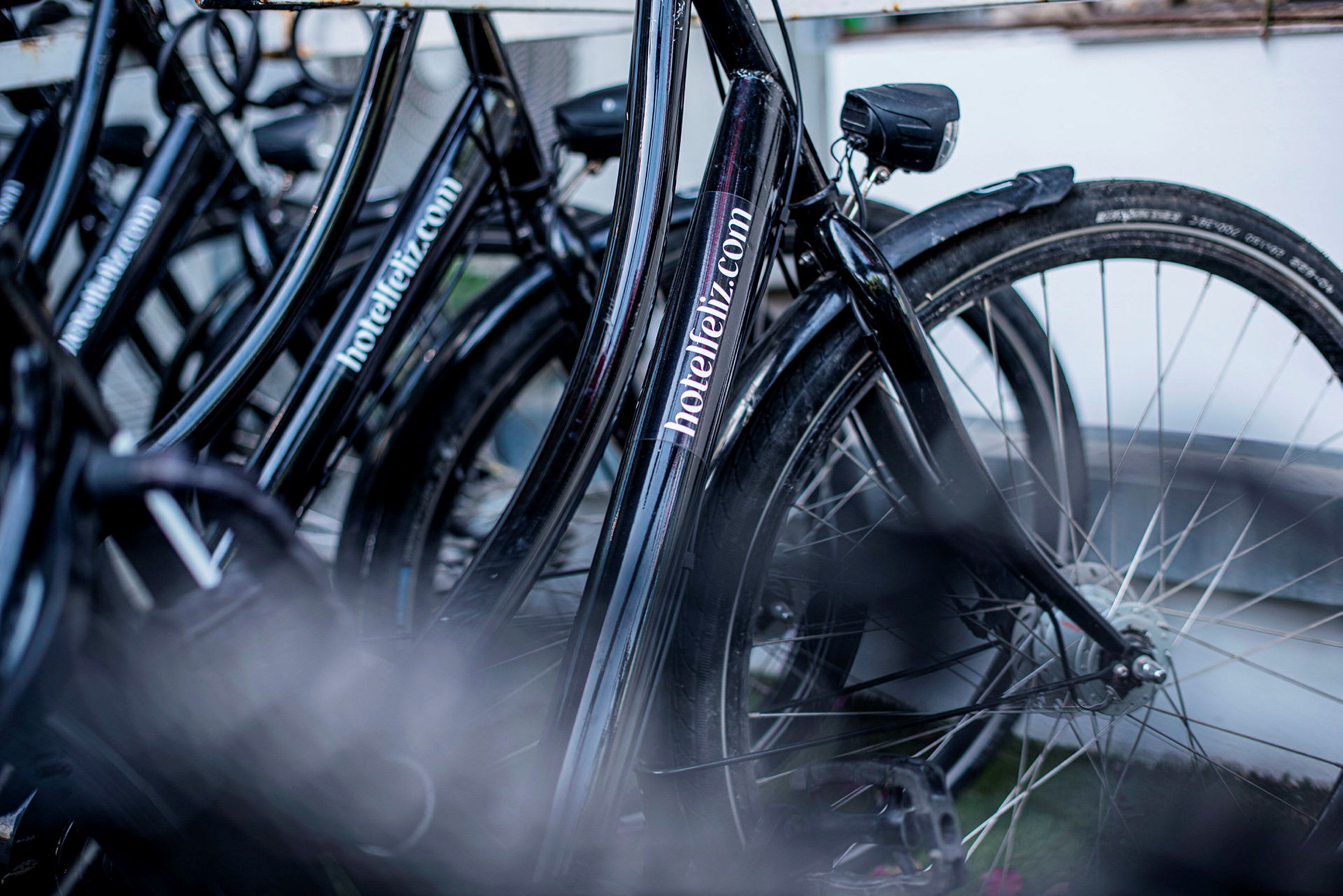 En rad av svarta cyklar med texten 'hotelfeliz.com' på ramarna. (AI-genererad text)