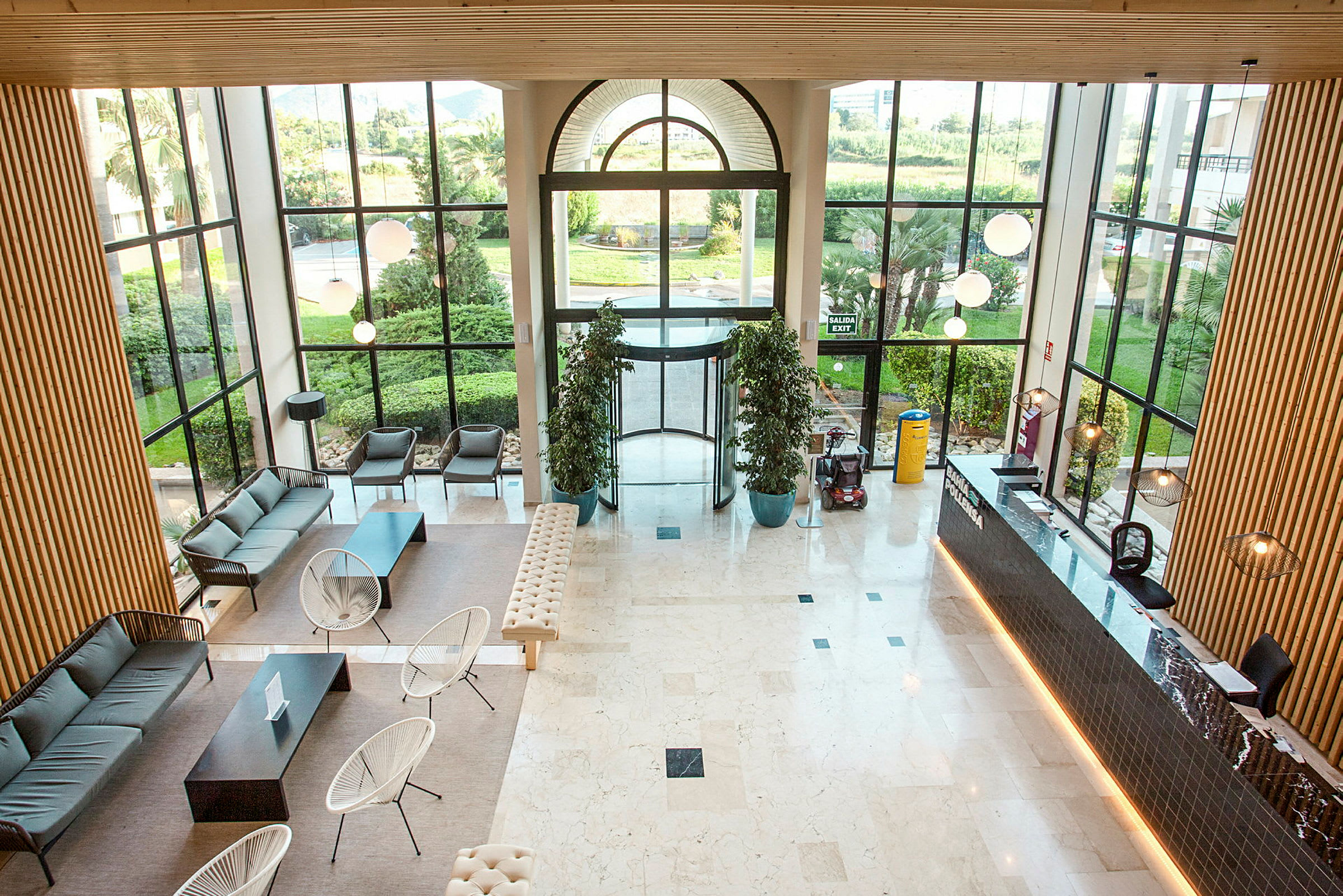 En modern hotellobby med sittmöbler, receptionsdisk och stora fönster som släpper in naturligt ljus. (AI-genererad text)