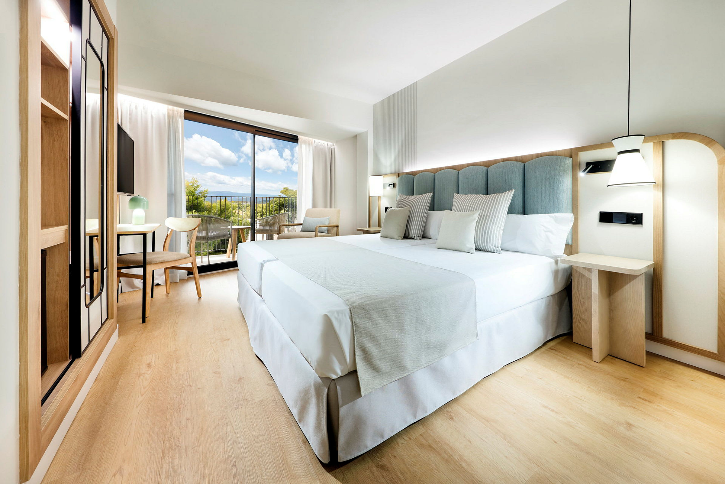 Ett modernt hotellrum med en stor säng, trämöbler och en balkong med utsikt. (AI-genererad text)