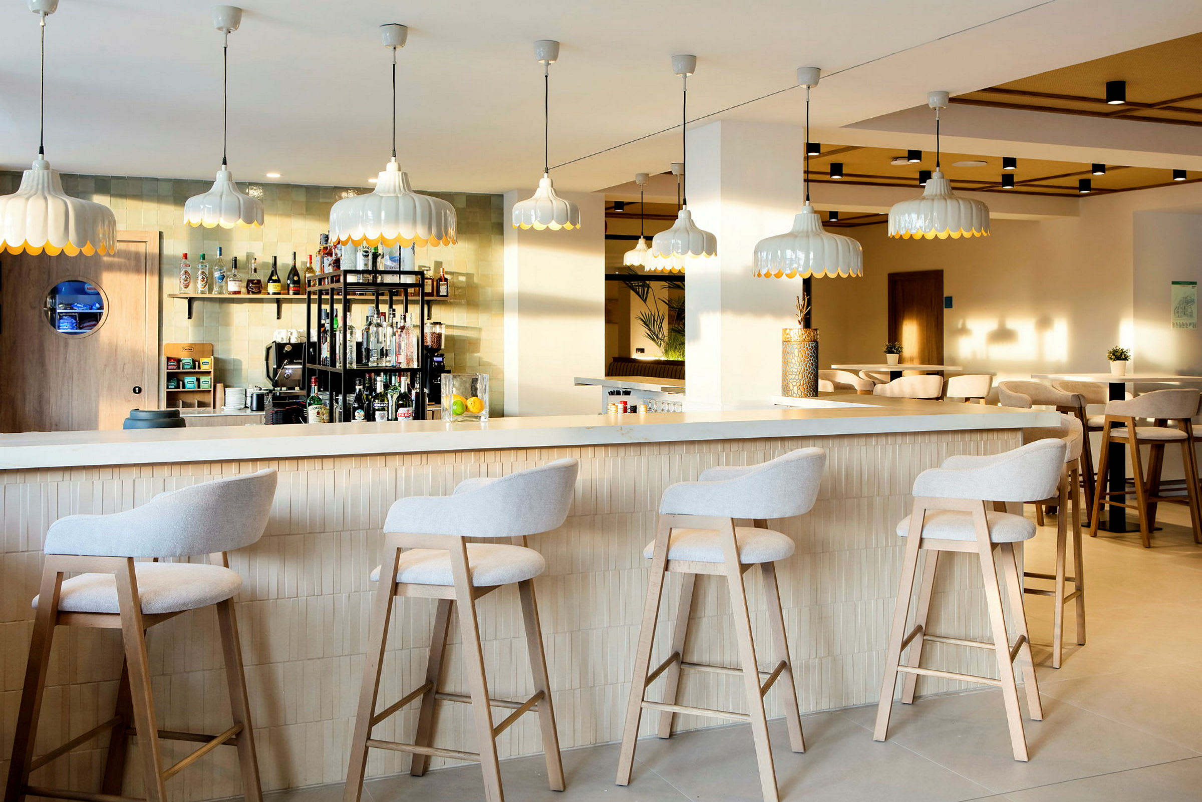 En modern bar med höga stolar vid disken och stilfulla lampor hängande från taket. (AI-genererad text)