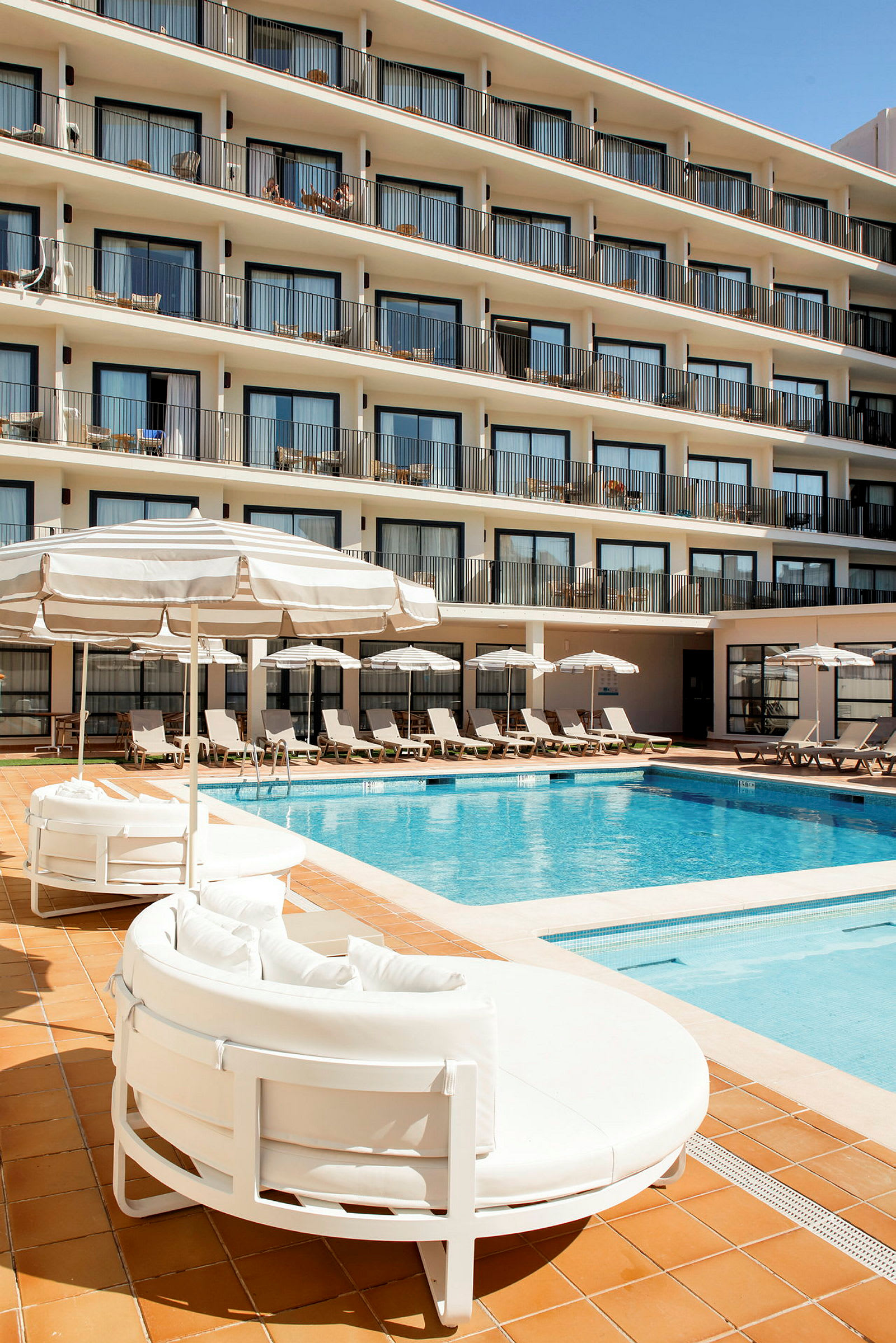 Utomhuspool vid ett hotell med solstolar och parasoller. (AI-genererad text)