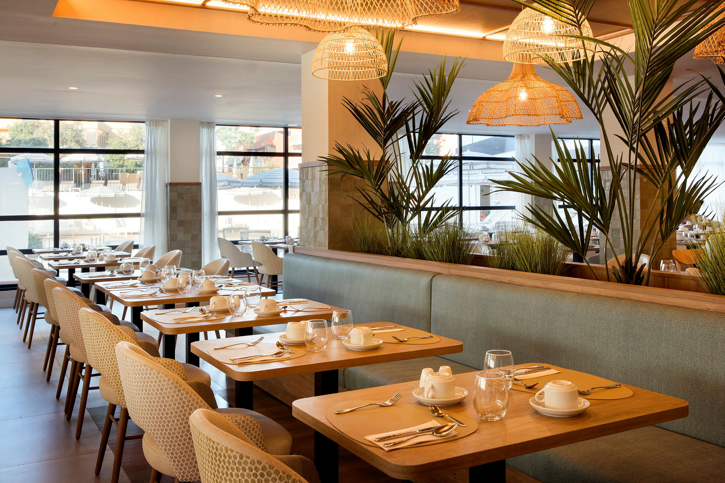 En elegant restaurang med dukade bord, bekväma stolar och grönska som dekor. (AI-genererad text)