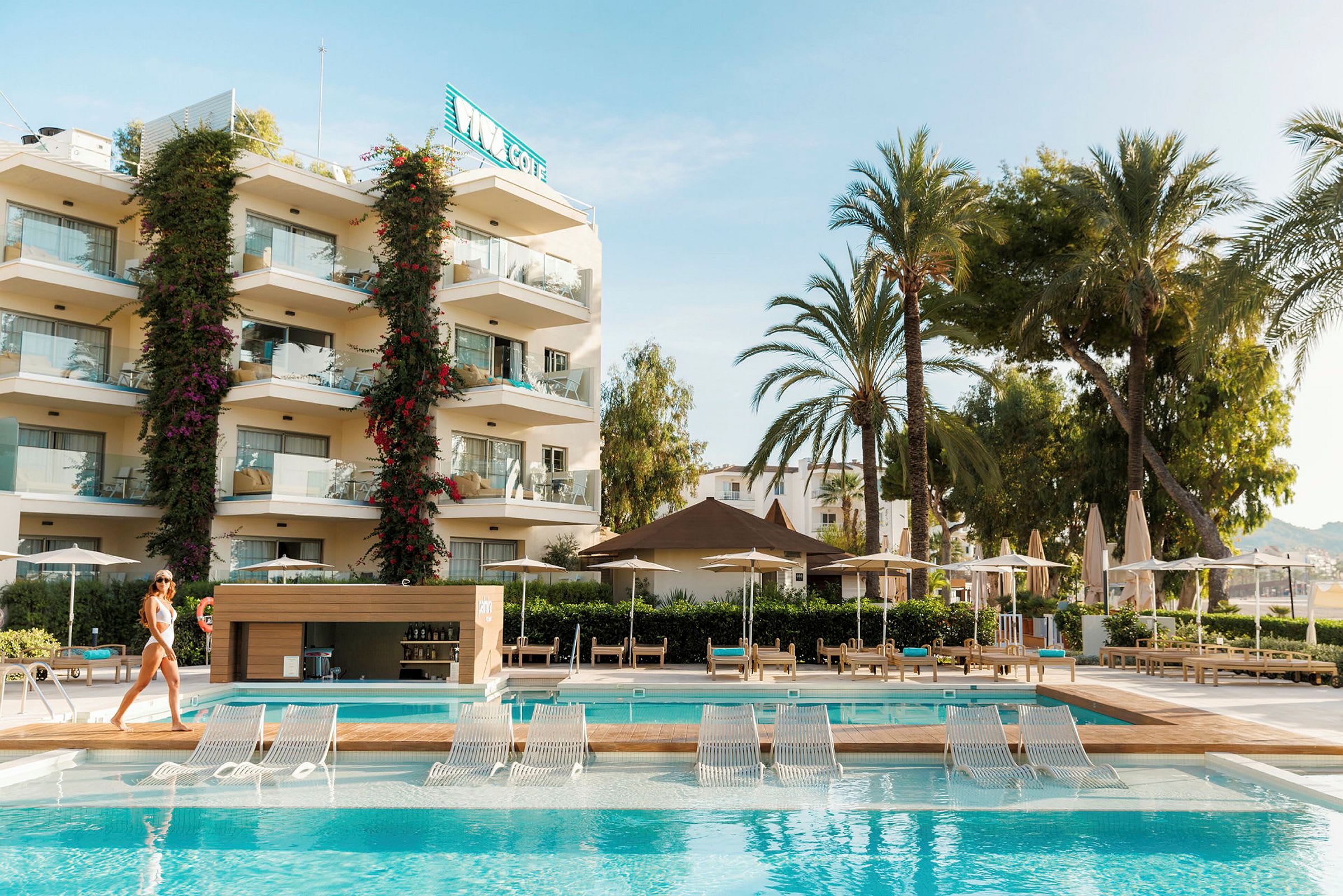 Hotellområde med pool och solstolar, omgiven av palmer. (AI-genererad text)