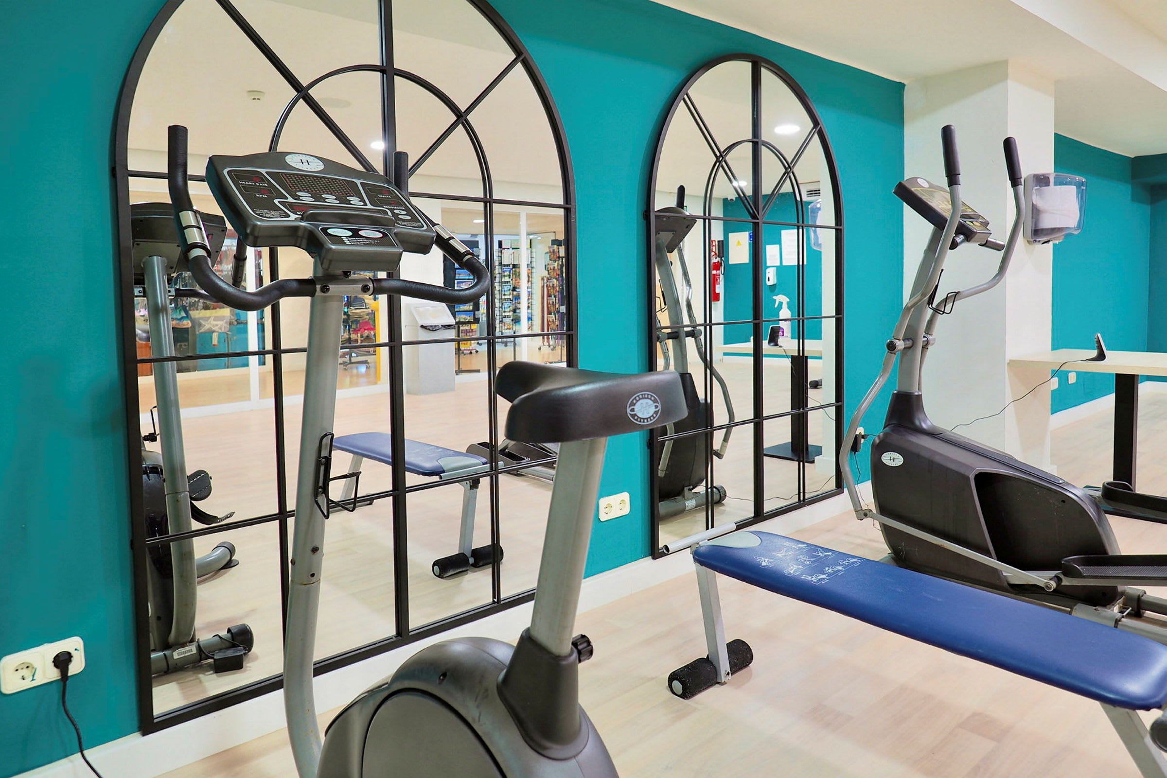 Ett gym med träningsmaskiner och spegelvägg. (AI-genererad text)
