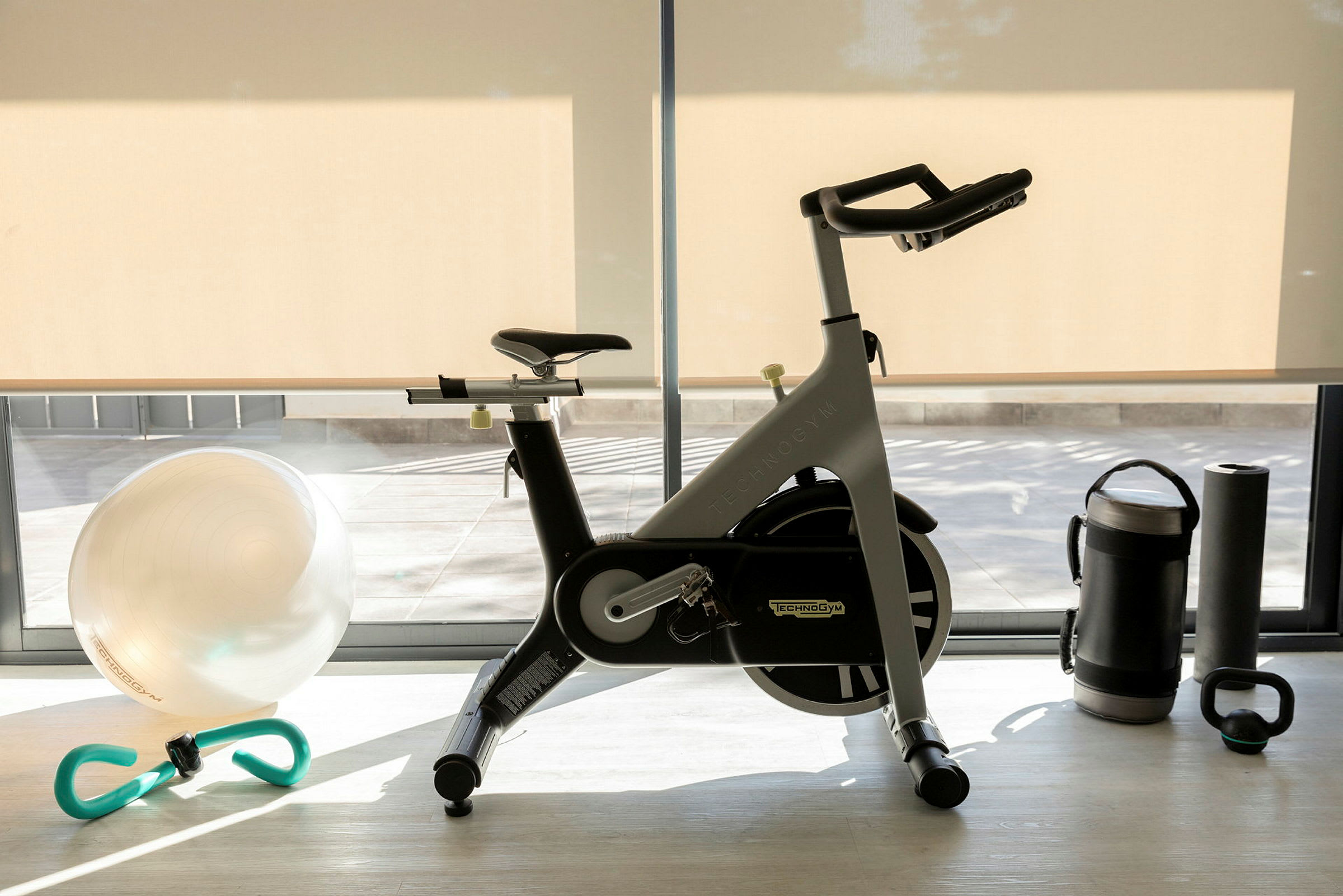 Ett gym med en motionscykel, en träningsboll, en vattenflaska, en yogamatta och en kettlebell. (AI-genererad text)