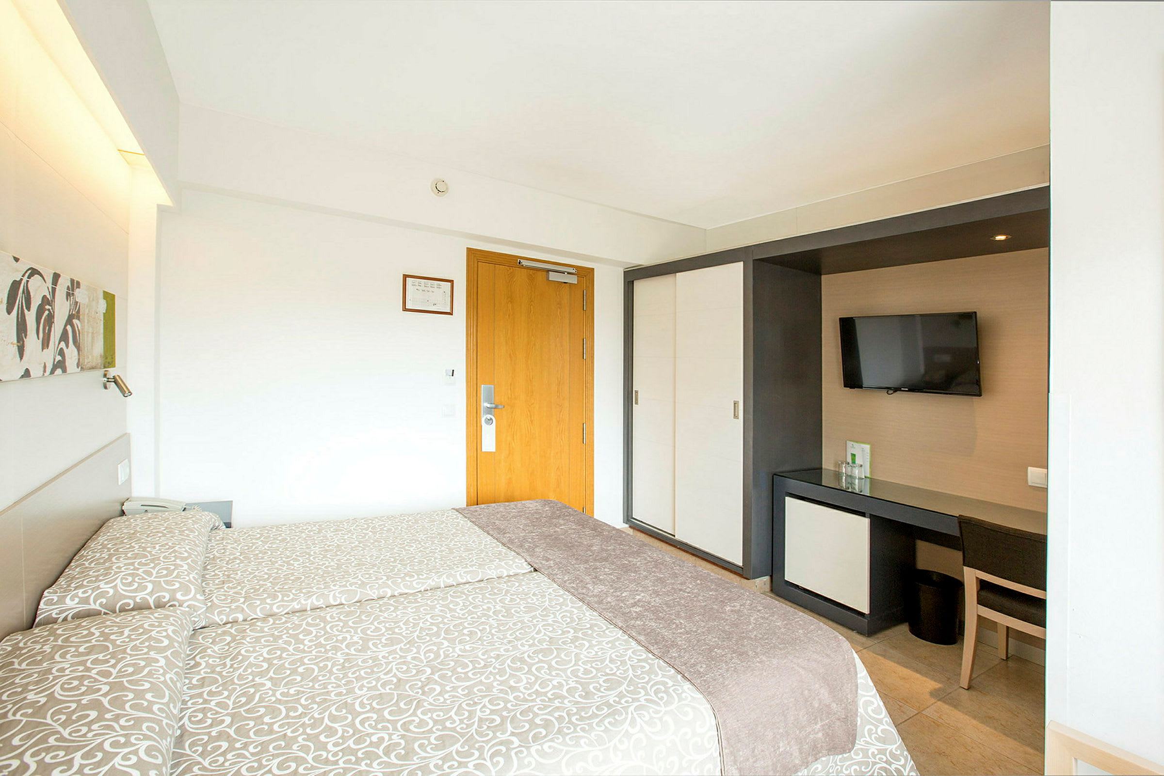 Hotellrum med två sängar, TV och skrivbord. (AI-genererad text)