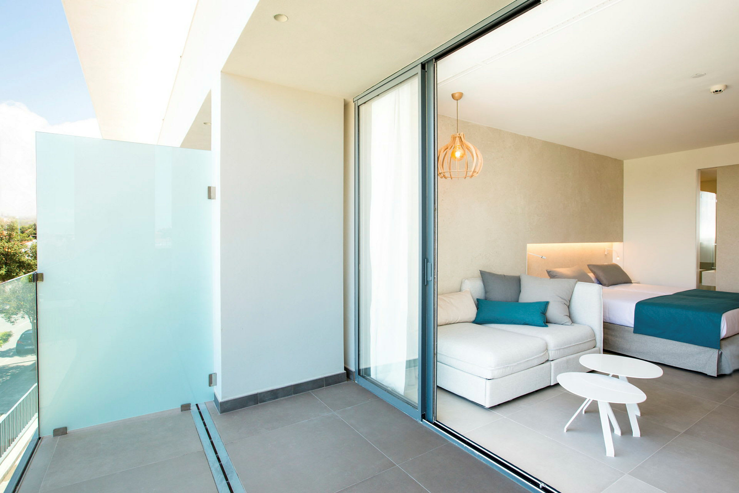 En modern hotellrumsvit med en balkong, vita möbler och en dubbelsäng. (AI-genererad text)