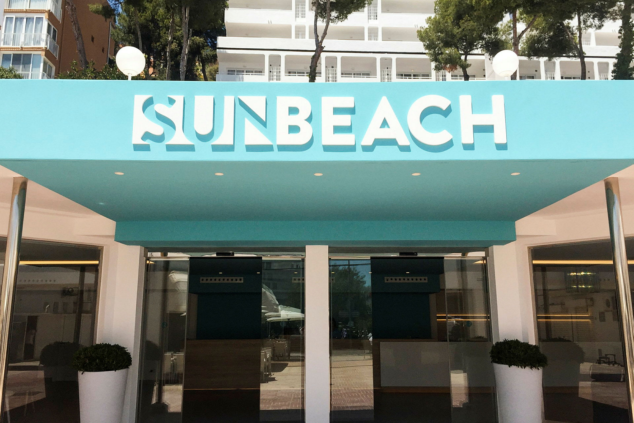 Ingången till Sun Beach-hotellet med turkosa detaljer. (AI-genererad text)