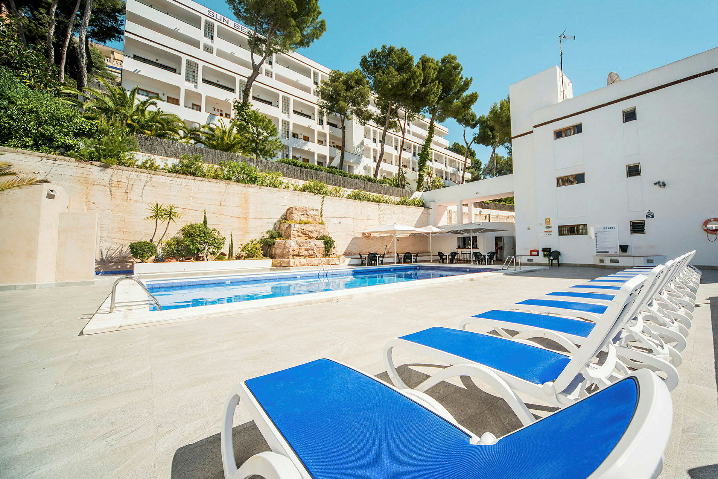 Solstolar vid en pool med hotellbyggnad i bakgrunden. (AI-genererad text)