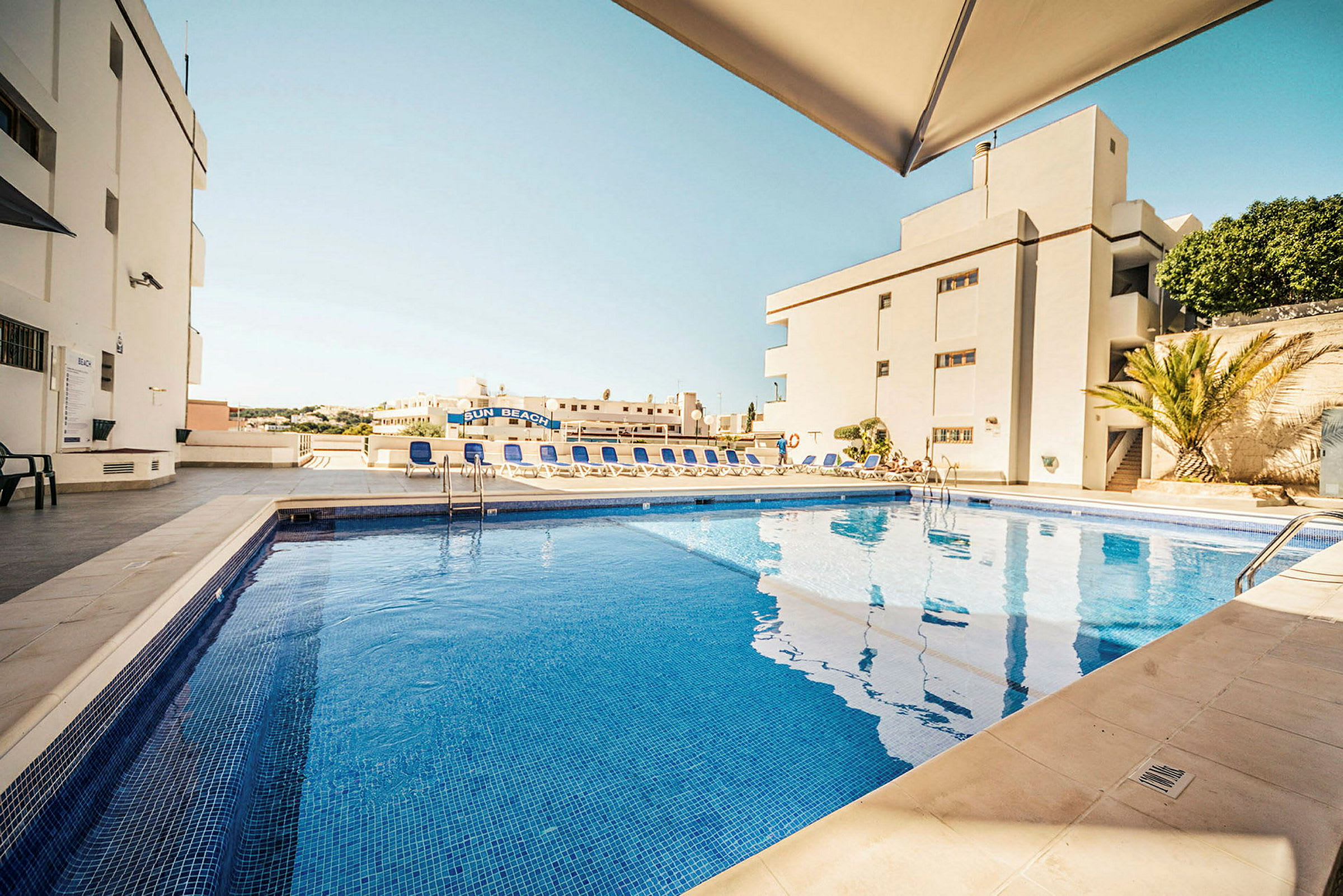 Simningspool vid ett hotell med solstolar och parasoll. (AI-genererad text)