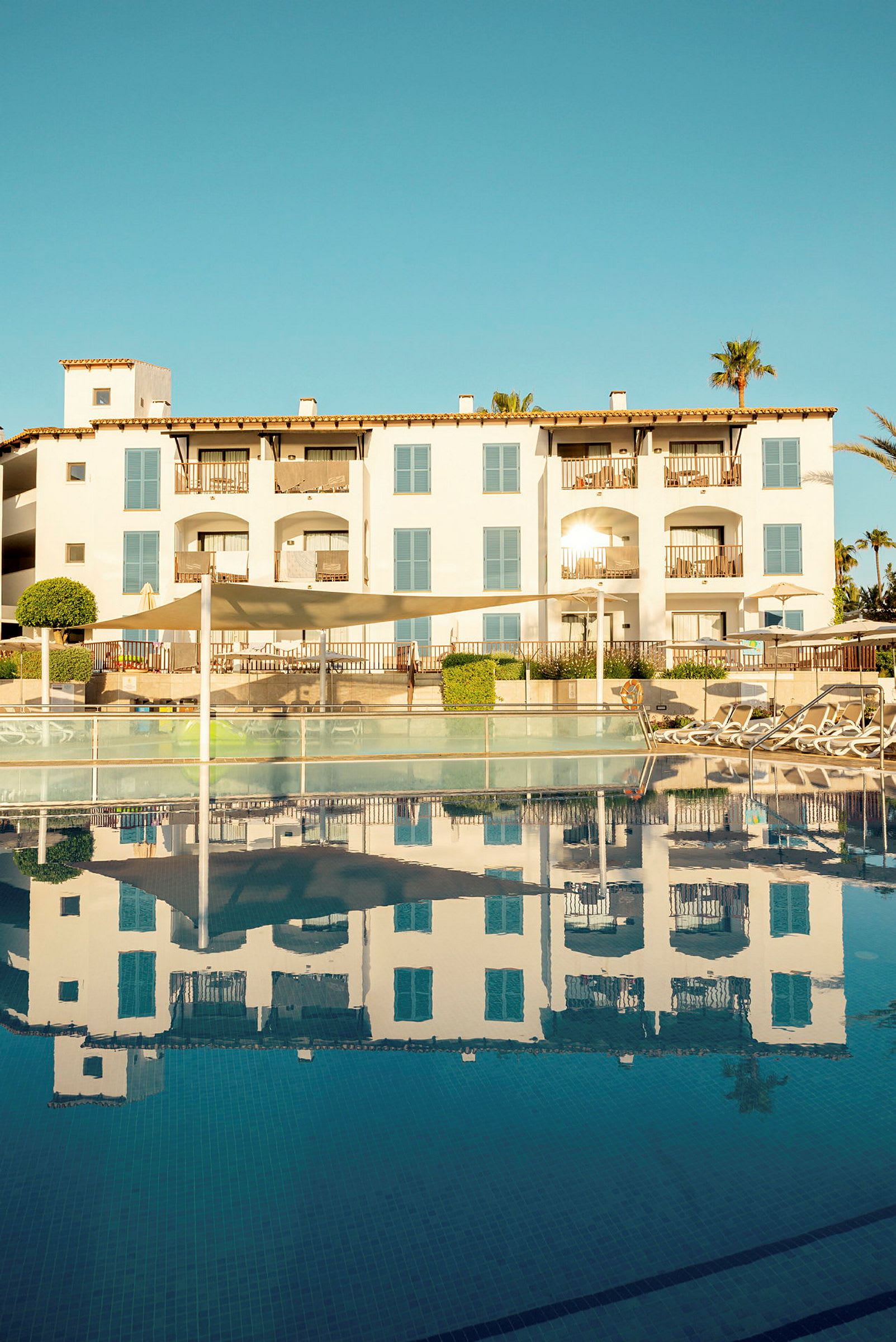Hotellbyggnad med balkonger och pool i förgrunden. (AI-genererad text)
