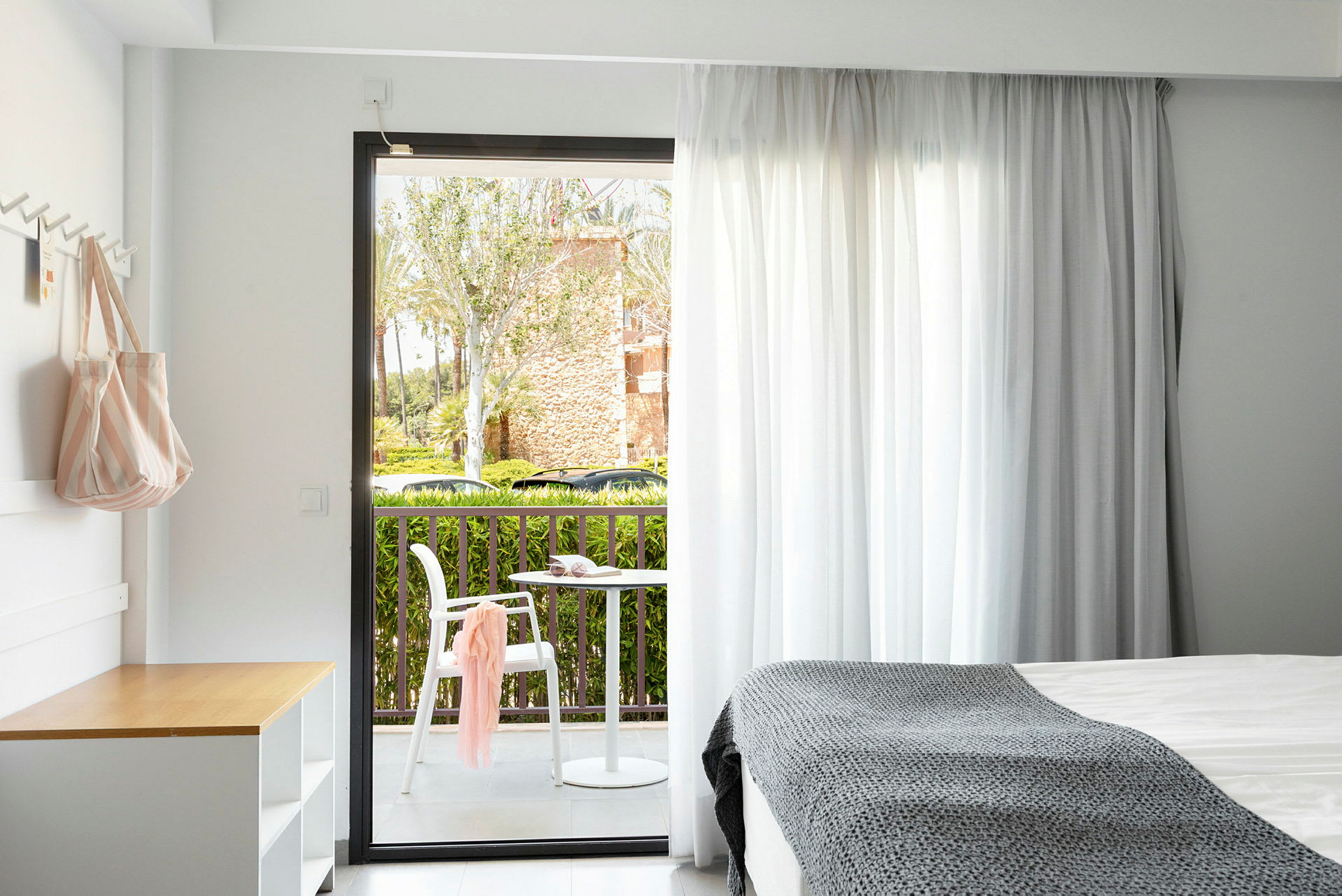 Ett hotellrum med utsikt mot en balkong med bord och stol. (AI-genererad text)