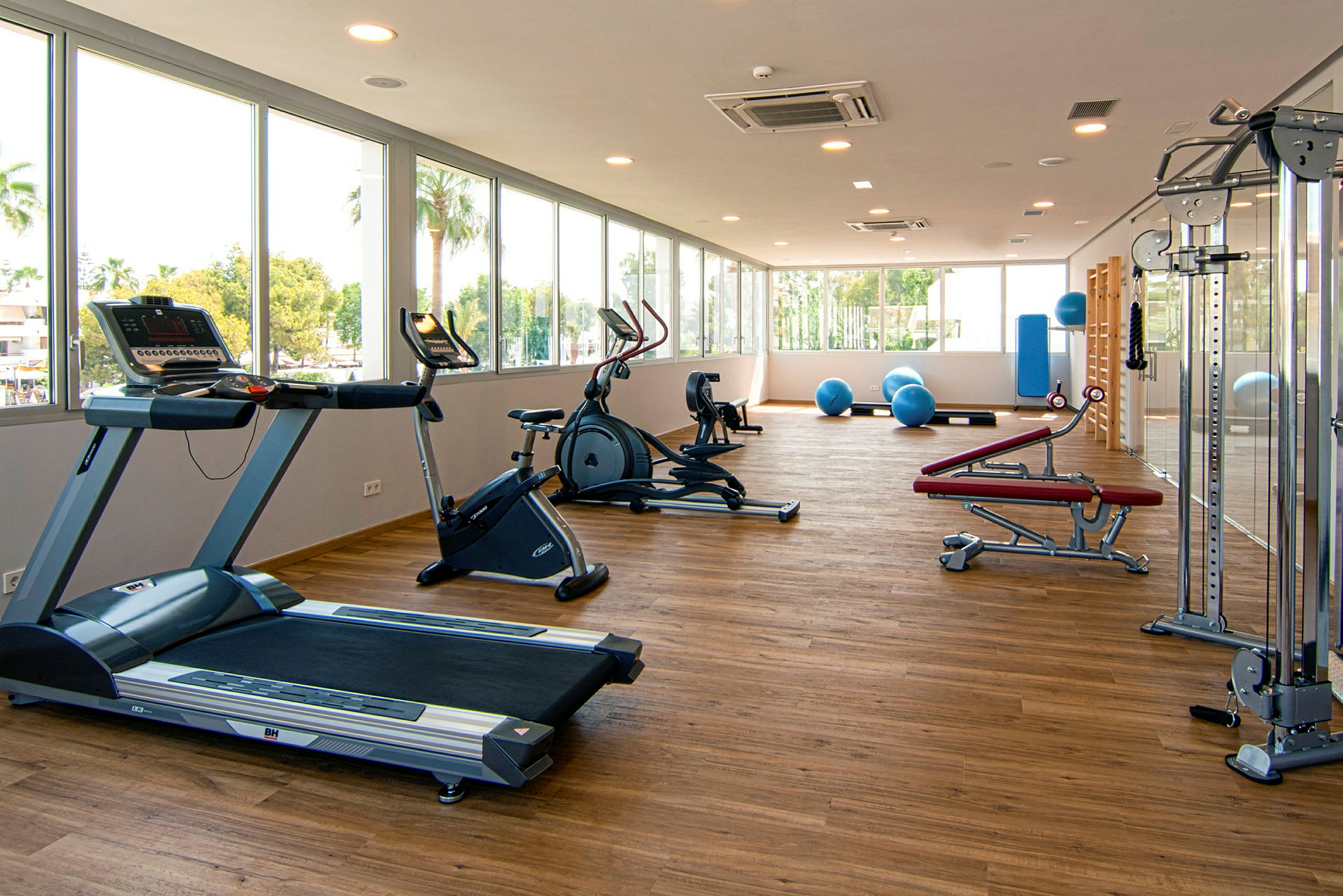 Ett luftigt gym med träningsmaskiner, fria vikter och pilatesbollar. (AI-genererad text)