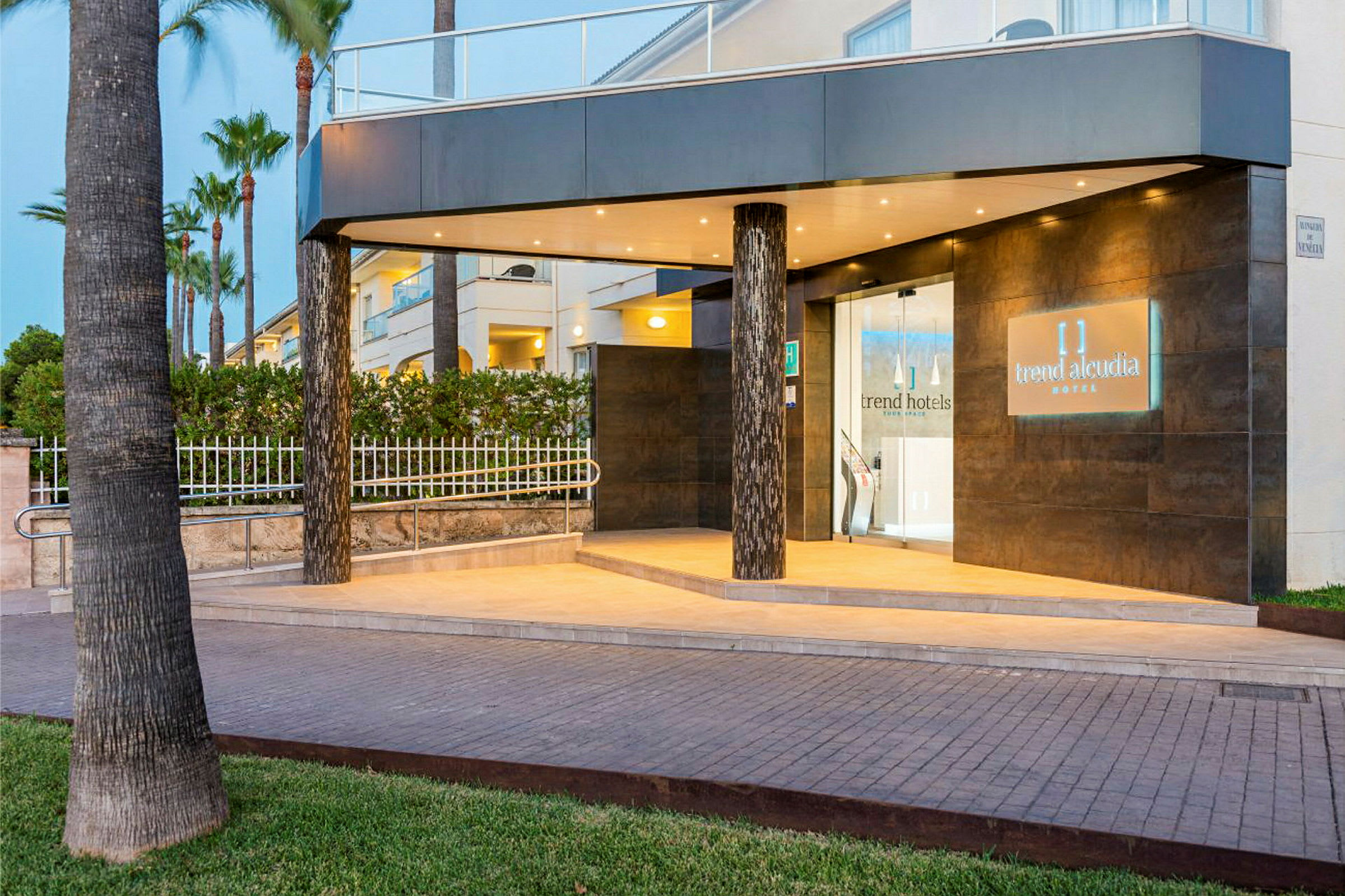 Ingången till ett hotell med belysning och namnet 'Trend Alcudia Hotel' på en skylt. (AI-genererad text)