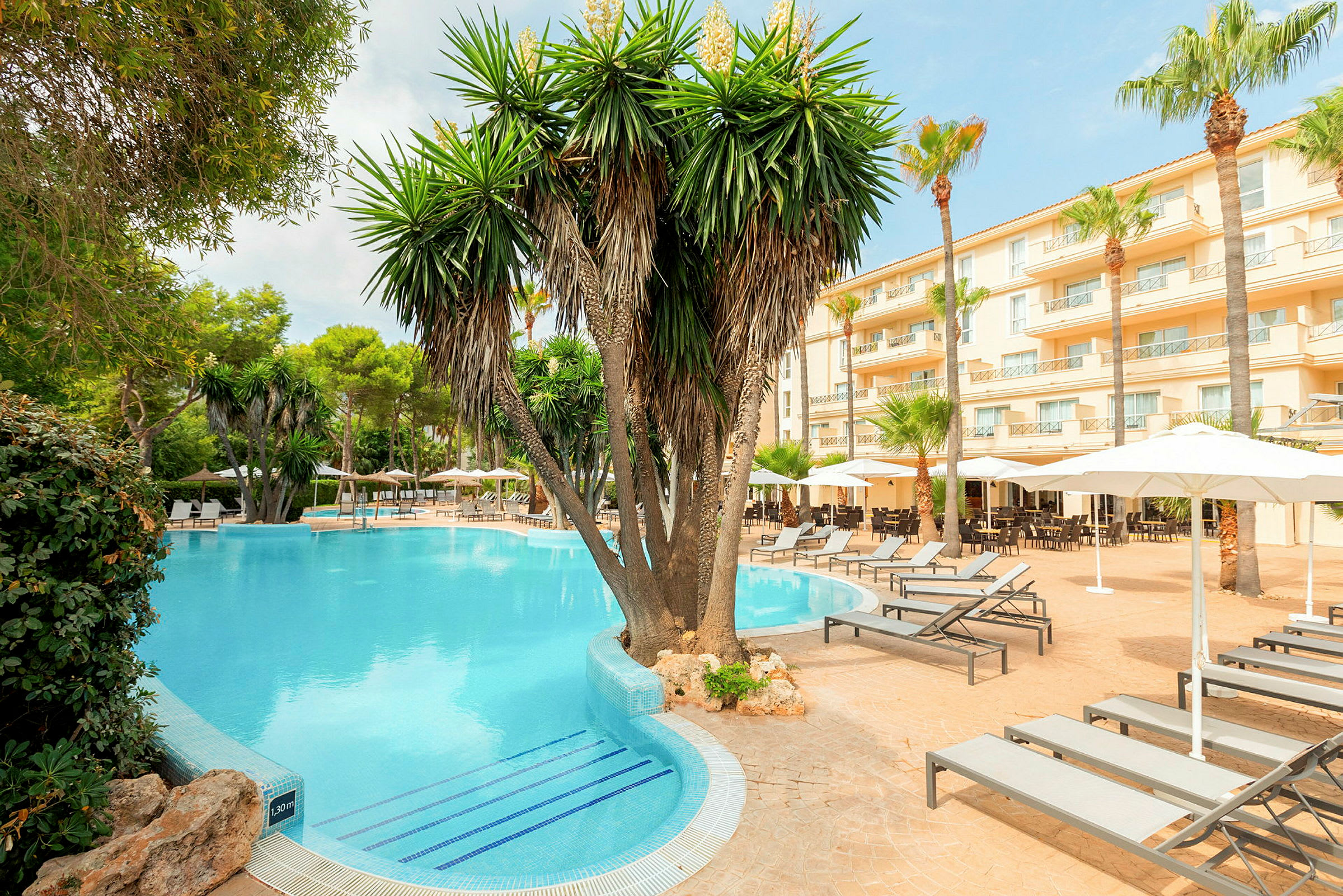 Hotellområde med pool, palmer och solstolar. (AI-genererad text)