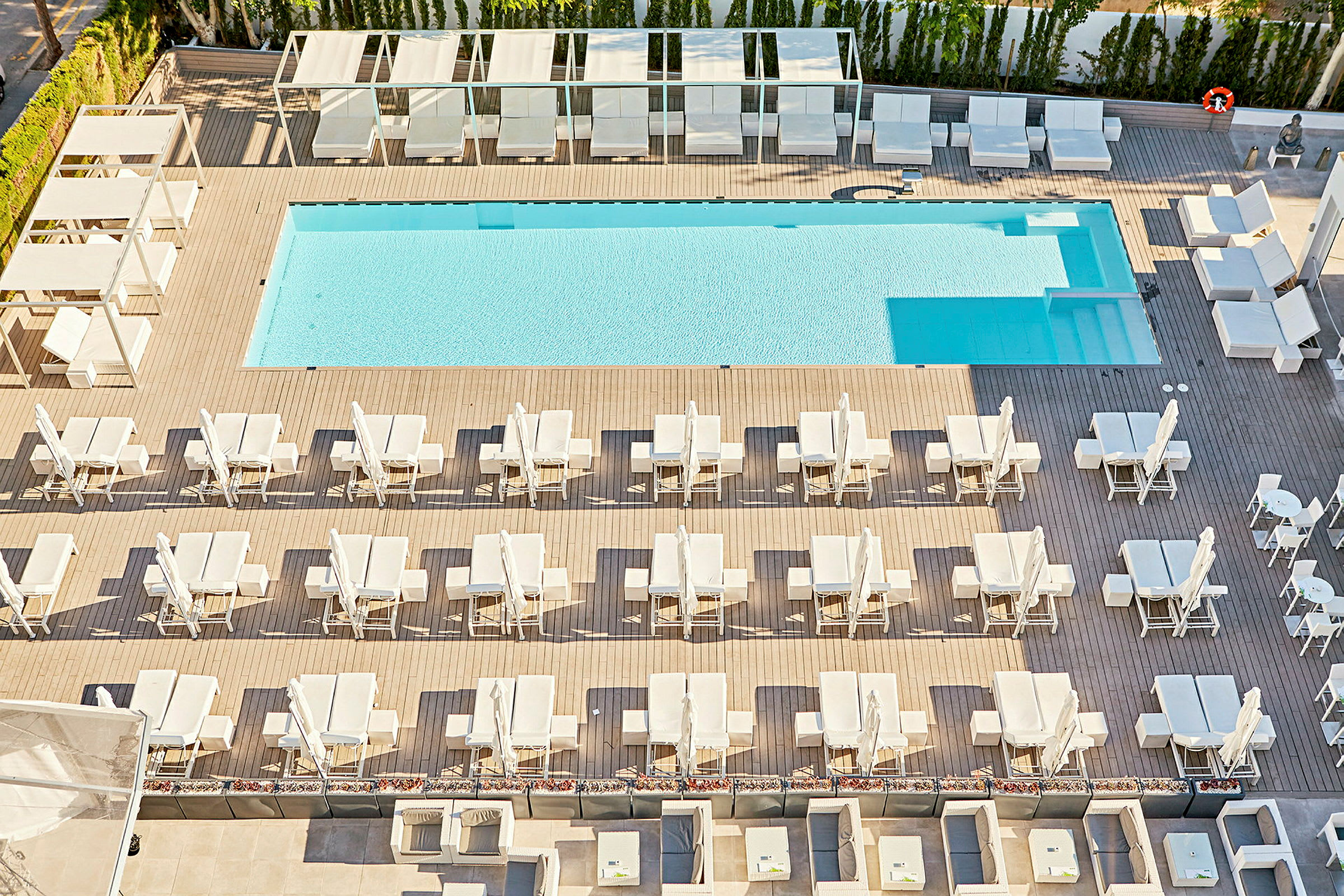 En pool med omgivande solstolar och parasoller på ett däck. (AI-genererad text)